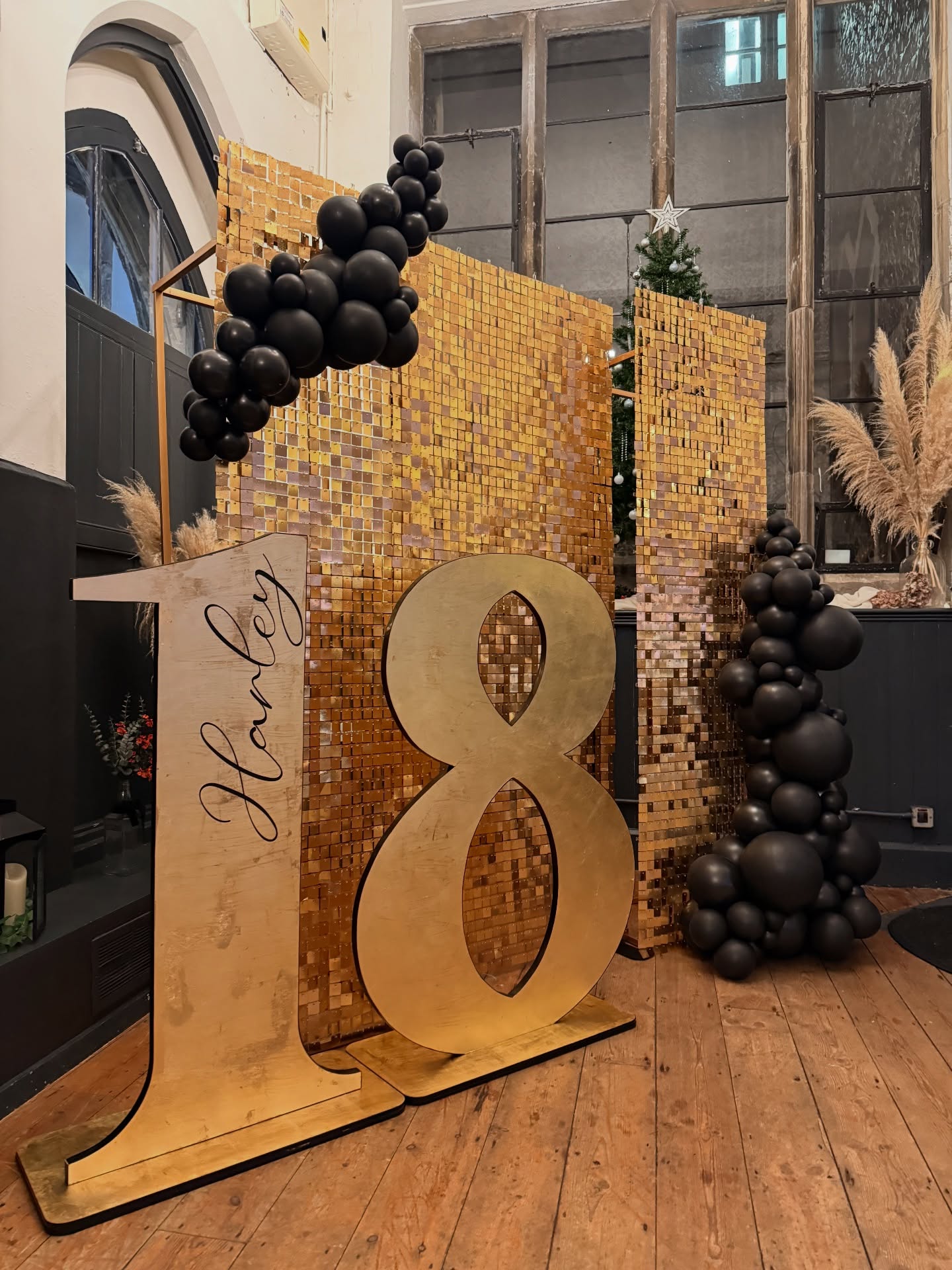 ~ Harley’s 18th ~
We were back at the Priory last weekend for a true 18th Birthday Bash 🖤
With a popular colour scheme like Black & Gold, it can be difficult to make it truly bespoke, so the devil really is in the details.
We opted for a staggered shimmer wall to bring depth to the backdrop, accompanied by a monochrome garland in a black pearl finish to contrast the gold shimmer; personalisation added to our GORGEOUS (and may I add, fully handmade 🙋🏼♀️) 4ft textured numbers; gold leaf black glass bubbles to dress the tables; and layered gold leaf in with our curvaceous plinth garland to complete the set ✨