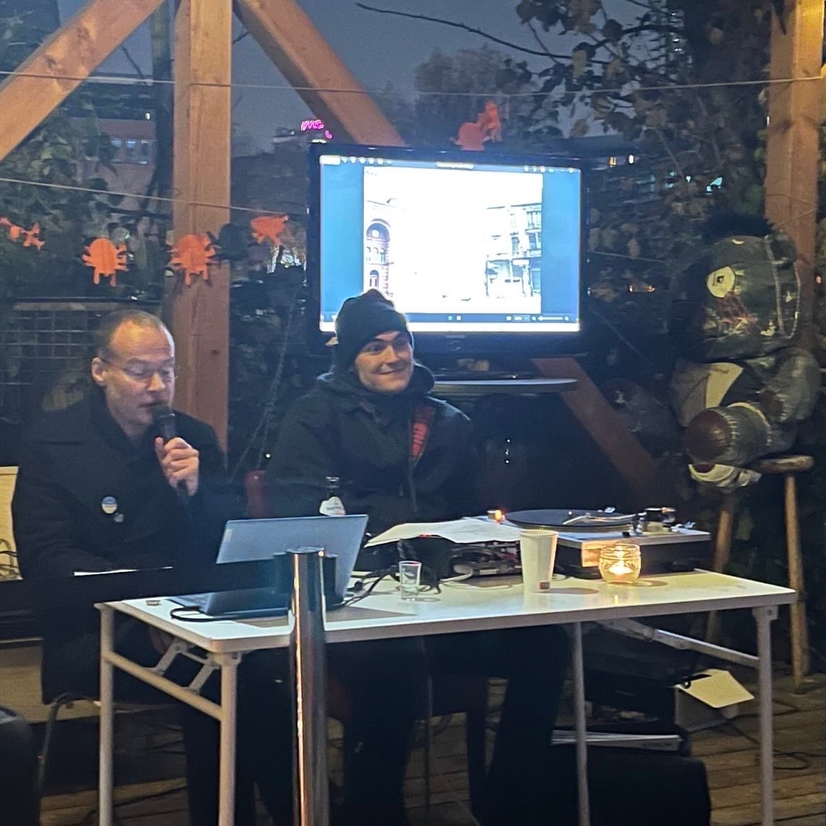 In dieser Abendveranstaltung in der Teepeeland-Siedlung ging es darum, dass oft verklärte West-Berlin der 1980er mit seiner ungewöhnlichen Subkultur darzustellen, in seinen zeithistorischen Kontext einzubetten und es auch kritisch hinsichtlich seiner Schattenseiten und möglicher Bezüge zur Gegenwart zu evaluieren. Die entsprechende Darstellung sollte aus einem bebilderten Vortrag (die Photos stammten primär aus dem Archiv der Geschäftsführung) und passenden Songs aus der „Szene“ jener Zeit bestehen. Letztere wurden von dem Musiker/Künstler Leon Baumgarl mithilfe eines Plattenspielers präsentiert. Zuerst wurden die allgemeinen geopolitischen Hintergründe des damaligen West-Berlins beleuchtet. Dann ging es um die konkreten Details der damaligen Situation der „Halbstadt“. Im zweiten Abschnitt ging es dann um die konkreten Ausprägungen der West-Berliner Subkultur. Im dritten Abschnitt der Veranstaltung ging es dann darum, der unkritischen Verherrlichung des West-Berlins der 1980er entgegenzuwirken, indem auf die konkreten Schattenseiten verwiesen wurde.