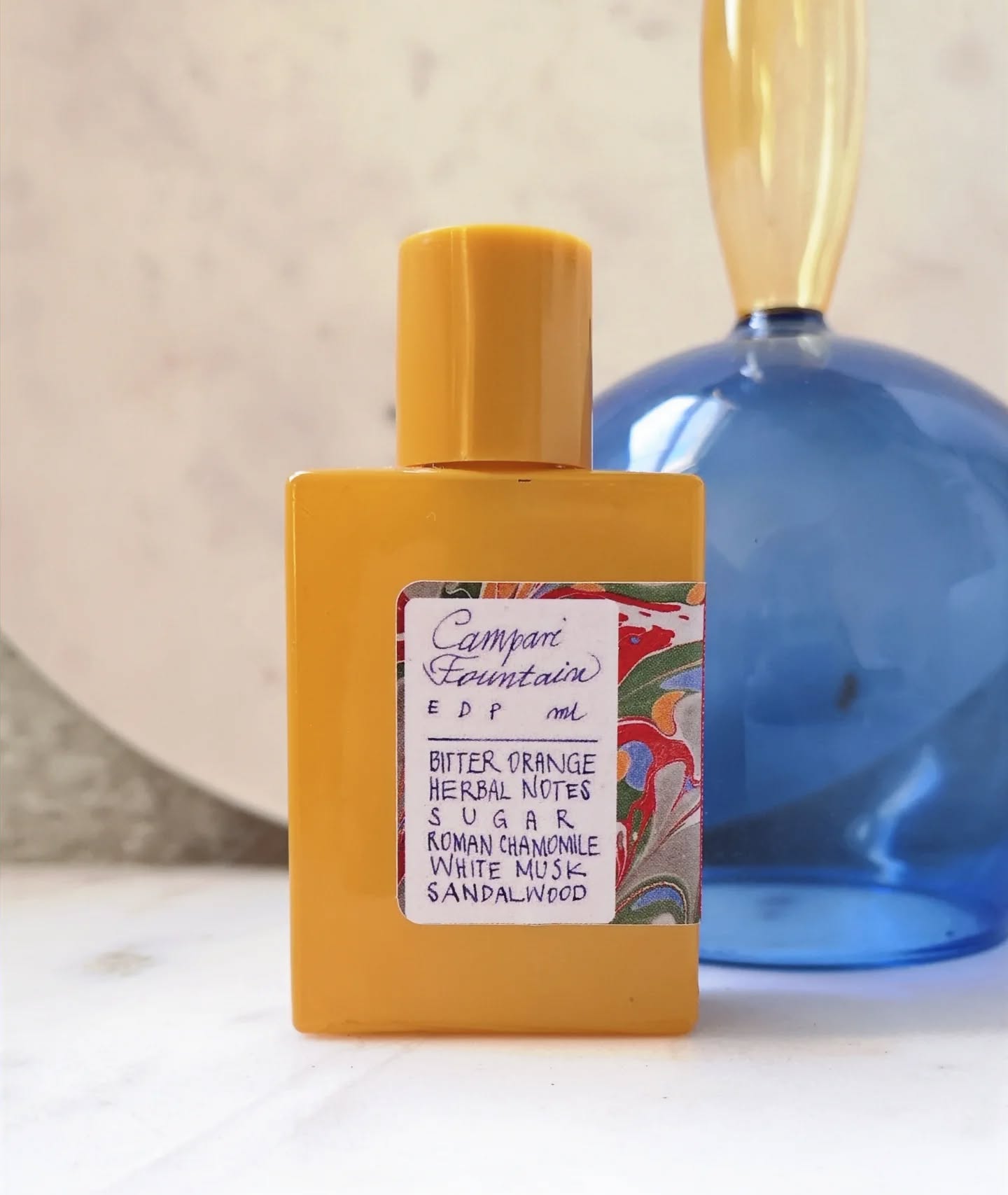 Who would have thought a citrus-centered fragrance could be a bestseller this time of year? Our Campari Fountain doesn't have the weight some people seek in winter perfumes, but it warms you up with sunshine and brightness - the complete opposite of the gloom we're getting right now.
The composition opens with a burst of bitter orange (lovely cold pressed oil sourced in Calabria) that is extended into the heart of the perfume using substances naturally occurring in orange juice, twigs, and leaves. With it, just like in real Campari, come delicate herbs and just enough of a sugary note to balance the vegetal bitterness. The sandalwood background has nothing of the sharpness or heaviness some woody notes can bring; it's velvety, warm and satisfying. We've seen so many people smiling when smelling it for the first time!