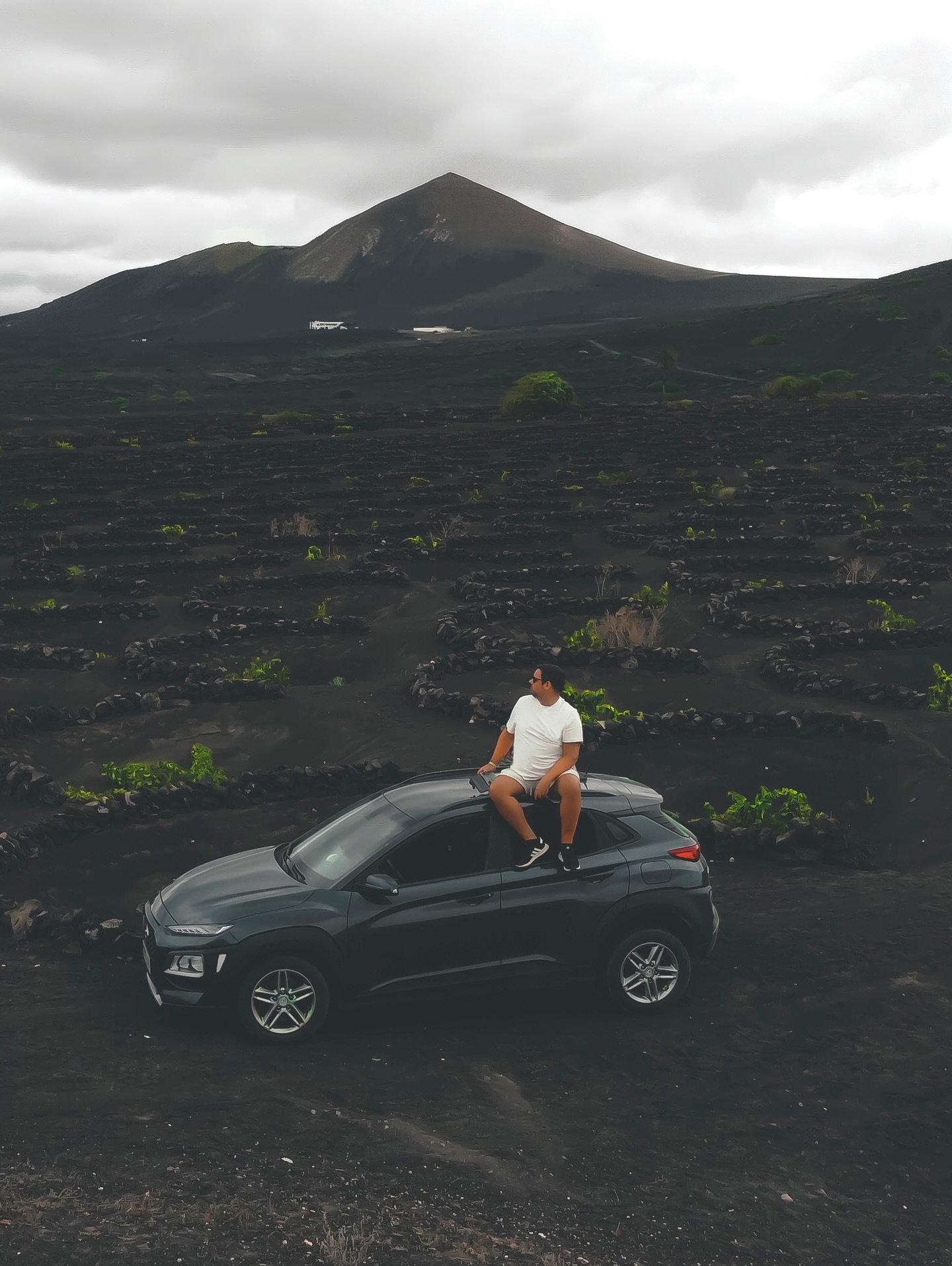 Schwarze Lava statt Sandstrandromantik, harte Kontraste statt Postkartenidylle. Straßen ziehen sich wie Linien durch eine Landschaft, die eher nach Mond als nach Badeurlaub aussieht. Ihr fahrt, haltet an, steigt aus, schaut. Mehr passiert oft nicht. Und genau das bleibt hängen.
Die erste Begegnung ist meist die Straße. Asphalt, schnurgerade, links und rechts Lavafelder. Kaum Häuser, kaum Farben. Dann plötzlich diese kleinen grünen Punkte. Reben, die in Mulden wachsen, geschützt von halbkreisförmigen Steinmauern. Landwirtschaft unter Extrembedingungen. Lanzarote erklärt sich nicht, Lanzarote zeigt.
Ihr merkt schnell, wie ruhig die Insel ist. Kein Lärm, keine großen Gesten. Selbst die Orte wirken zurückhaltend. Weiße Häuser, grüne oder blaue Türen, Patina an den Wänden. Nichts geschniegelt, nichts geschniegelt wirken wollend. Alles darf altern. Alles darf bleiben.
Im Inselinneren wird es weit. Hügel, Vulkankegel, schwarze Ebenen. Das Auto wird klein, Ihr noch kleiner. Wer hier anhält und einfach mal stehen bleibt, versteht die Insel besser als in jedem Museum. Lanzarote braucht Zeit. Und ein bisschen Stille.
An der Küste ändert sich das Bild, aber nicht der Ton. Das Meer ist präsent, aber nie kitschig. Kein türkisfarbener Dauerfilter, eher dunkles Blau, oft rau. Wind gehört dazu. Wellen auch. Die Insel macht klar, wer hier das Sagen hat.
Was Lanzarote besonders macht, ist die Konsequenz. Architektur, Landschaft, Lebensgefühl, alles folgt einer Linie. Keine Hotelburgen mitten im Nirgendwo, keine Effekthascherei. Vieles davon geht auf César Manrique zurück, aber selbst ohne Namen spürt Ihr den Gedanken dahinter. Diese Insel will nicht überbaut werden. Sie will gelesen werden.
#lanzarote
#kanarischeinseln
#vulkanlandschaft
#roadtrip
#fokusfernweh
