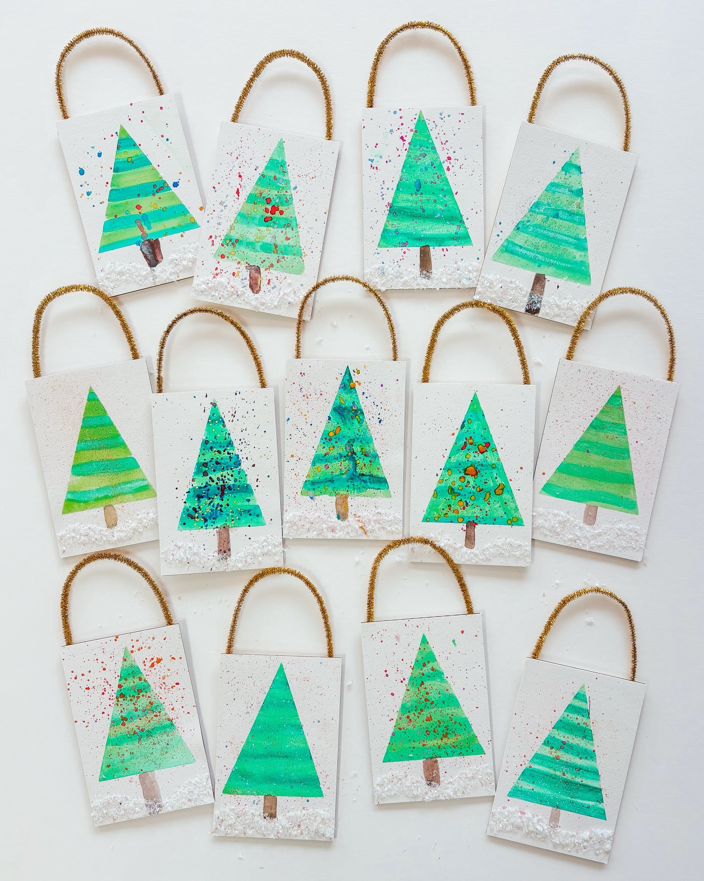 Our artists explored resist and splatter paint techniques as they created these sweet watercolor tree ornaments. A sprinkle of iridescent snow makes each one shimmer - perfectly magical for the Christmas tree!