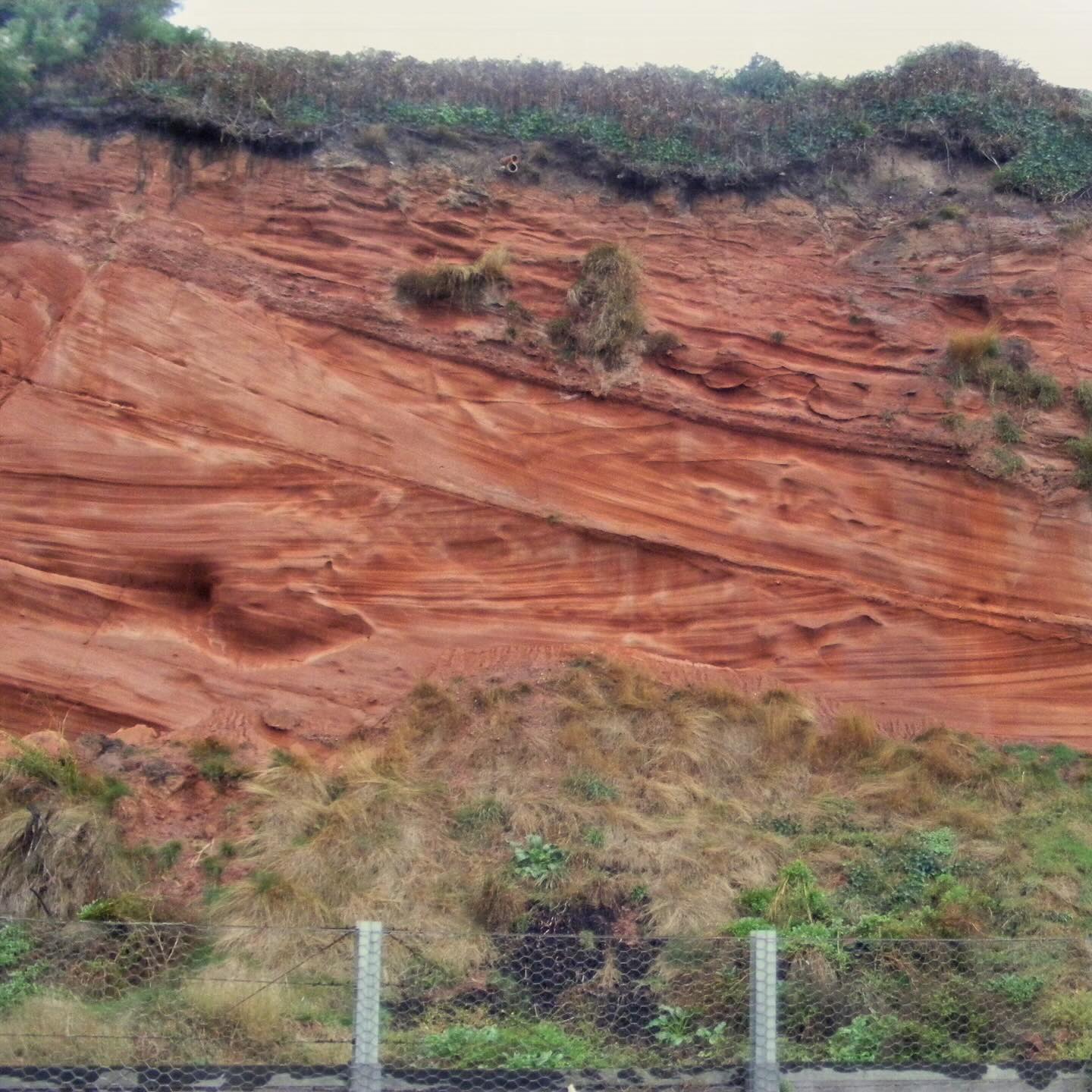 On the train heading up to North Devon for Christmas, which includes one of my favourite train journeys combining love of geology with trains - Dawlish.
The railway runs precariously between the sea and the bright red cliffs, famously doing battle (and losing) with coastal erosion.
It is stunning though, and the geology of these cliffs is spectacular.
They are made of rocks collectively known as the New Red Sandstone - Permo-Triassic sedimentary rocks that formed in an arid, mountainous environment around 250 million years ago.
The preceding Variscan Mountains were eroding away, shedding vast quantities of sediment down through canyons, alluvial fans, and braided river systems.
Surrounding these river systems were flood plains, and dune systems developed, evolved and migrated.
There are several sections in the cliffs where you can see the sweeping crossbedding that would have formed from windblown sand migrating across the desert in huge dune systems.
The bright red colour comes from iron oxide, or rust, that coats the sediment grains and cements them together. This is typical in hot, arid climates that promotes oxidation of iron-rich minerals like haematite.
The railway was constructed in 1844 as part of Brunel’s Great Western Railway. Whilst it is a beautiful stretch of railway it is incredibly vulnerable to coastal erosion and is constantly undergoing engineering work.
In the famous 2014 storms the sea wall was breached and a section of the railway was washed away, effectively cutting off Cornwall from the mainline. A £35 million repair project saw the line reopen in just 8 weeks.
#dawlish #dawlishbeach #dawlishwarren #greatwesternrailway #brunel #sandstone #triassic #desert #sanddune #sedimentary #sedimentaryrock #sedimentology #devon #devoncoast #southdevon #walkingdevon #exploredevon #lovedevon #devongeology #ukcoast #geology #geologyrocks #geolife #geologist #geologistsofinstagram #learninggeology #geoadventure #exploregeology #geologicalwonders #geologylife