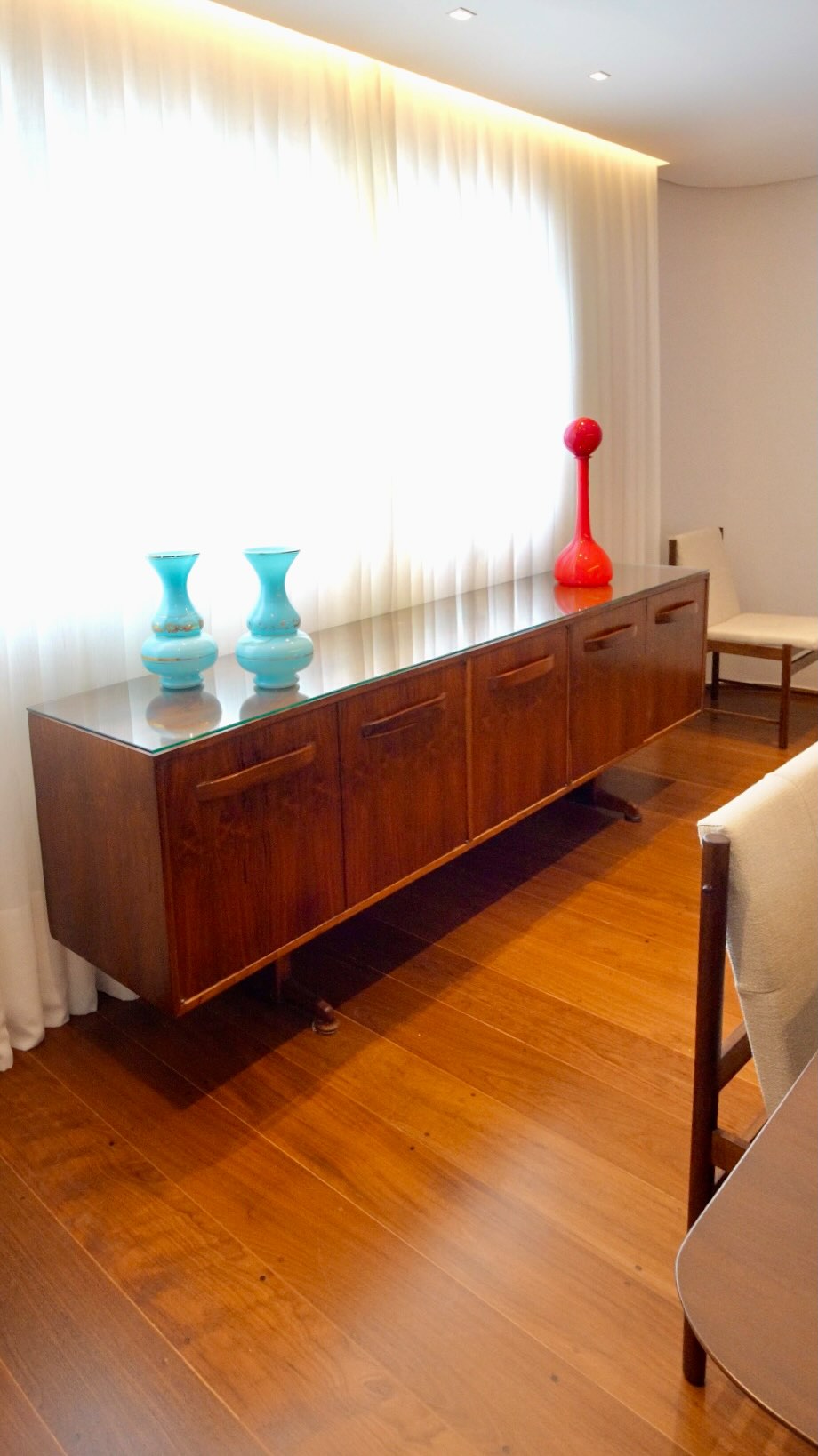 No projeto de ambientação deste apartamento nos Jardins, um dos pontos centrais é o buffet da Novo Rumo, criado por Francesco Scapinelli nos anos 1960. A peça, feita em jacarandá da Bahia e preservada em estado excepcional, mostra como o mobiliário modernista brasileiro continua a dialogar com naturalidade com interiores contemporâneos.
Os cinco módulos de portas e as três gavetas internas oferecem um armazenamento generoso, enquanto os puxadores orgânicos esculpidos na madeira evidenciam o refinamento artesanal que marcou a produção da Novo Rumo. A base elevada, leve e precisa, equilibra o volume do móvel e revela a elegância das proporções concebidas por Scapinelli.
No ambiente, o buffet convive com a mesa de jantar contemporânea, cadeiras atuais e uma luminária escultural. Essa convivência confirma algo que sempre reforçamos na Lora Ronco: o bom design atravessa décadas sem perder relevância. Ele se adapta, se renova e encontra n
ovas leituras quando inserido em espaços de hoje.
Autêntico dos anos 1960, este buffet representa a excelência da marcenaria brasileira em jacarandá e a herança modernista que permanece viva nas casas contemporâneas.
Conheça esta e outras peças no acervo da Lora Ronco.
📍www.loraronco.com.br
📞 Fale conosco: (11) 99122-7578
#loraroncogaleria #designbrasileiro #braziliandesign #mobiliáriomoderno #mobiliariomodernobrasileiro