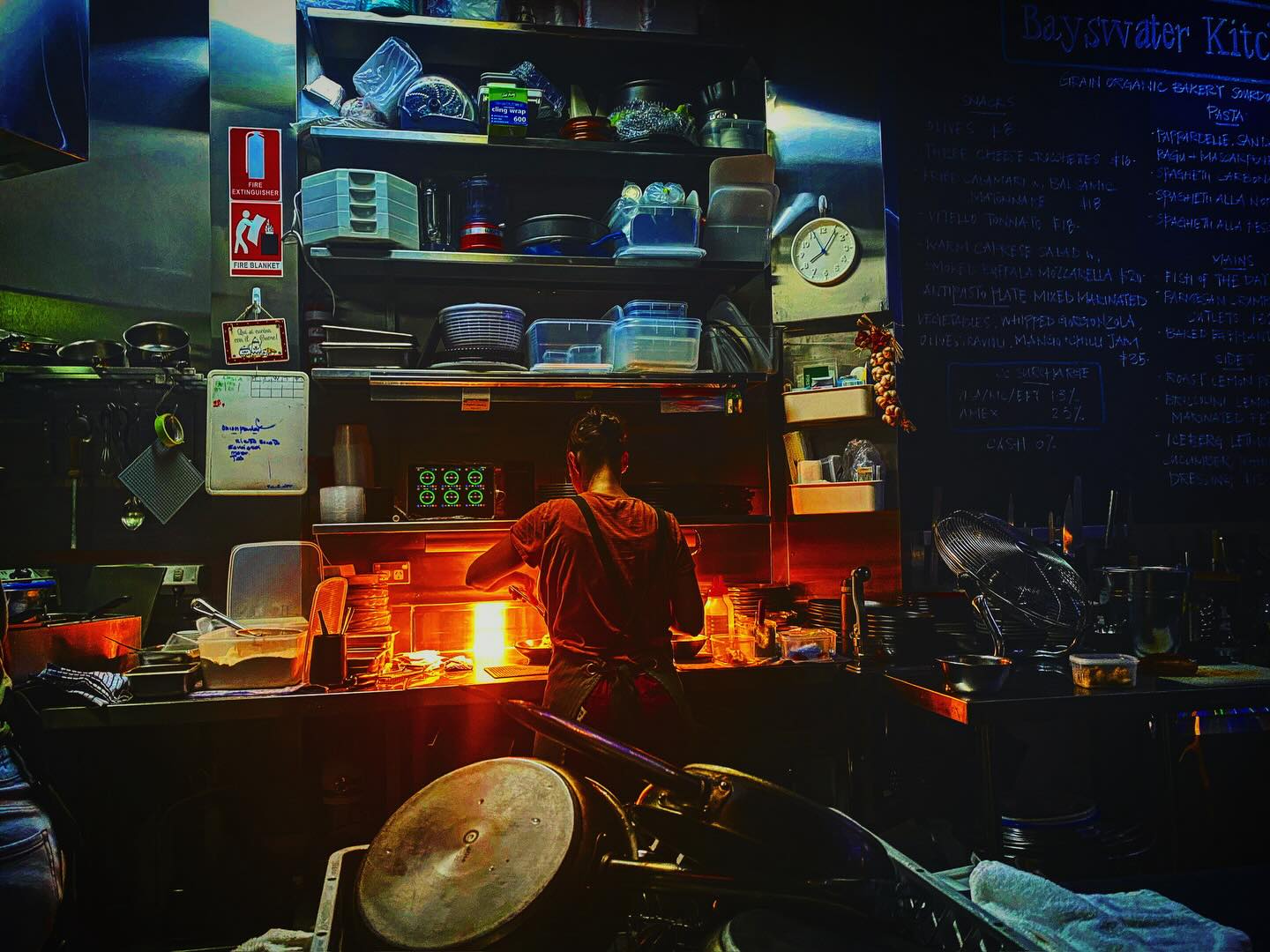 Fare thee well- This year KingsX Bayswater kitchenette shut off its lights, closed its doors. My last supper, eating alone. Sitting perched at the bar & counter, open to kitchen artistry & all action. Beacon of light, the source of deep nourishment beams into the space. Good fresh food, menu short, Italian, with synchronised team of 2 Alessias & Glenda, fluid movement a well-established smoo rhythm. The twinkle of light, a sparkle, a smile, a comfortable squeeze, the tables filled. A cake slice venue so small, friendly as if a family hearth. /Goodness generates as customers squish to let others by, a friendly tight squeeze. Short convivial conversation may bloom./ Alessia, chef with the fluid discipline of a martial art master within their mat performing stanzas, hers a chef’s choreographed movements, efficiency, grace & the zen of focus. Body stove ignition, a food alchemist’s secret? All visible Alessia misses not a beat her smile aglow. I don’t speak yet sit not alone, content with familiarity, remembrance of family, dance of food to kitchen table, welcomed, nourished, the embrace of belonging. Glenda, hospo queen of grace weaves between the 24 seats, with a ½ pavement outside of this a precious food jewel, her warmth, welcome, remembrance of customer, finely tunned hospo skills matches food quality. It’s been a a popular business plan designed for the diversity of KingsX’s locals / Balancing with acrobatics skill of spinning plates, dishes sparkle from machine, wipe, shelves, glasses polished to glistening, decanter amber to cherry reds filled & emptied or sparkling pops with condensations frosted hue. No movement superfluous, no moment wasted in their hospo dance, as plates gently land. (A show worthy of a golden buzzer on AGT, or crowds applaud on theatre stage?) Last supper, simple, delicious, pleasure lingers as senses luxuriate in the evening tide. Pasta’s perfect chew, sauce & mixed fish soaking up the last sensations of taste with the soft textures the pleasure of sound, crisp crunchy crusts mingling. Sip of wine & hug goodbye. Alessica’s wishes to birth another, which I look forward to, but it’s the last for these two friends on this dance