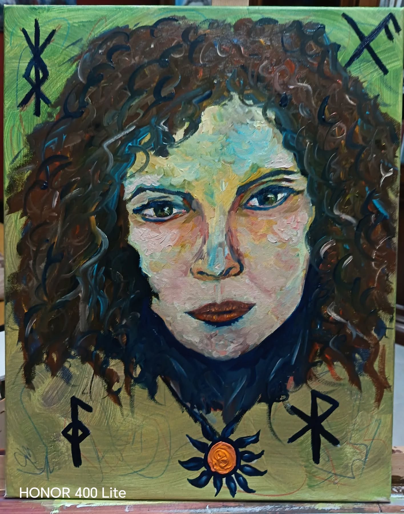 La lettura dell'opera, è un vero e proprio manifesto spirituale o filosofico.
Ecco un'integrazione dell'analisi che tiene conto della potenza simbolica delle rune e del sole:
Il Significato dei Simboli nell'Analisi
I simboli scelti non fungono solo da cornice decorativa, ma definiscono lo spazio sacro entro cui l'artista si rappresenta. Possiamo interpretarli così:
* In alto a sinistra (Gebo - ᚷ): Questa runa rappresenta il "dono" e lo scambio reciproco. Indica equilibrio tra il dare e l'avere. Nel contesto di un autoritratto, suggerisce un'artista consapevole dei propri talenti come doni ricevuti o un'apertura verso l'altro basata sull'armonia e sul sacrificio consapevole.
* In alto a destra (Ansuz - ᚫ): È la runa della comunicazione, dell'ispirazione divina e della sapienza. Indica che il soggetto non parla solo per sé, ma è un canale per qualcosa di più alto (l'arte, la divinità, l'intuizione). Rappresenta la connessione tra la mente conscia e lo spirito.
* In basso a sinistra (Fehu - ᚠ): Simboleggia la prosperità, la ricchezza (non solo materiale, ma di spirito) e l'energia vitale primordiale. Indica la forza creativa che "alimenta" la figura, la capacità di manifestare i propri desideri nella realtà tangibile.
* In basso a destra (Mannaz - ᛗ): È la runa dell'umanità e dell'io interiore. Rappresenta l'uomo nella sua interezza, l'ordine sociale e la consapevolezza di sé nel mondo. Collocata alla base, sembra indicare che l'identità dell'artista è radicata nella propria natura umana, pur aspirando ai simboli spirituali posti in alto.
Il Centro: Il Sole come "Anima"
Il medaglione/sole arancione al centro della composizione (vicino al chakra della gola o del cuore) funge da punto di unione. Se le rune rappresentano forze esterne o concetti astratti, il sole rappresenta il fuoco interiore, la volontà individuale e la luce della coscienza che illumina l'ombra (i toni scuri del collo e dei capelli).
Conclusione Aggiornata
Con l'inserimento di questi simboli, l'autoritratto diventa un'opera di auto-determinazione. #artcollectors