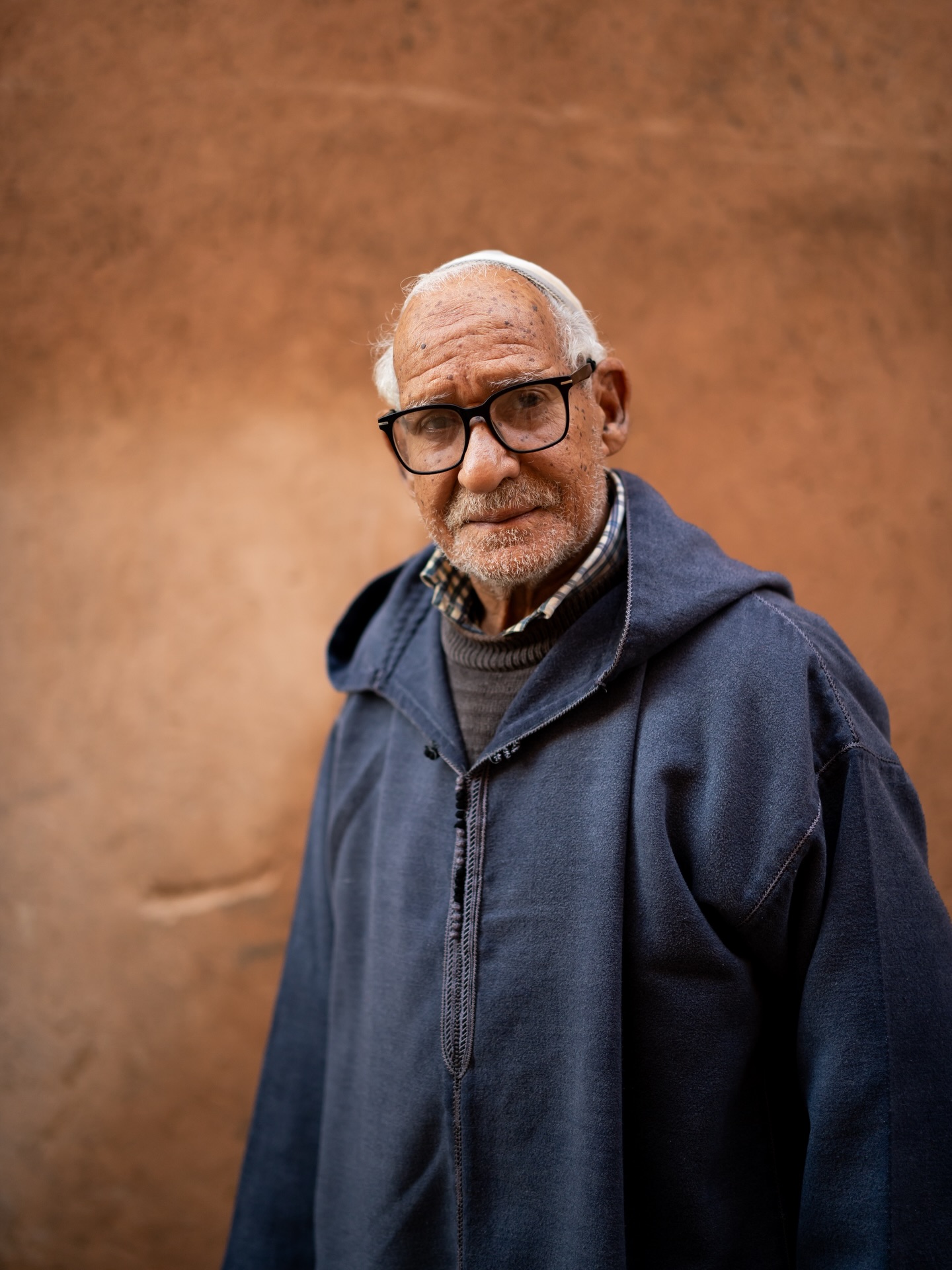 I was walking behind this man in Marrakech when I took this second photograph of him. I walked past him and asked if I could take his portrait. He agreed immediately. Lucky me—he was standing in front of a beautifully colored wall, wearing his natural expression and radiating warmth 💛
I didn’t ask him to pose or do anything at all. He was simply walking slowly, looking at me.
What I love about older Moroccan men is that they don’t change their expression when I photograph them. They remain exactly as they are, gazing deeply into my lens. No masks, no poker face—just their pure soul reflected in their eyes ✨