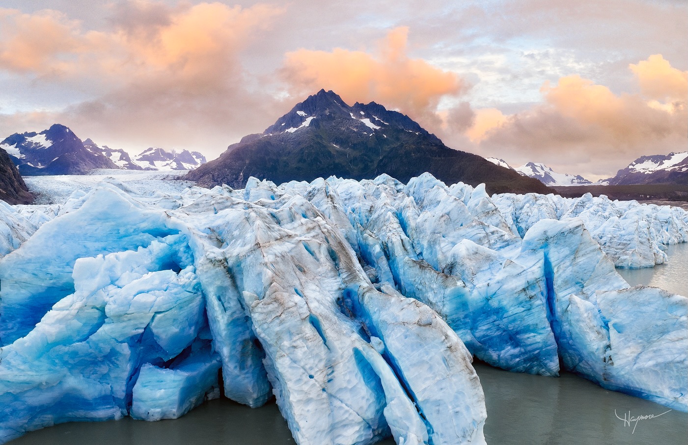 This massive ice wall was over 100’ tall. It moved slowly into the glacial lagoon carved by the immense weight and pressure. At first glance, it seems frozen and unmovable. Returning day after day allows one to see the subtle changes and the glacier moving.
Small icebergs break off, tumble and flip upside down, and drift as the wind pushes them towards the ocean.