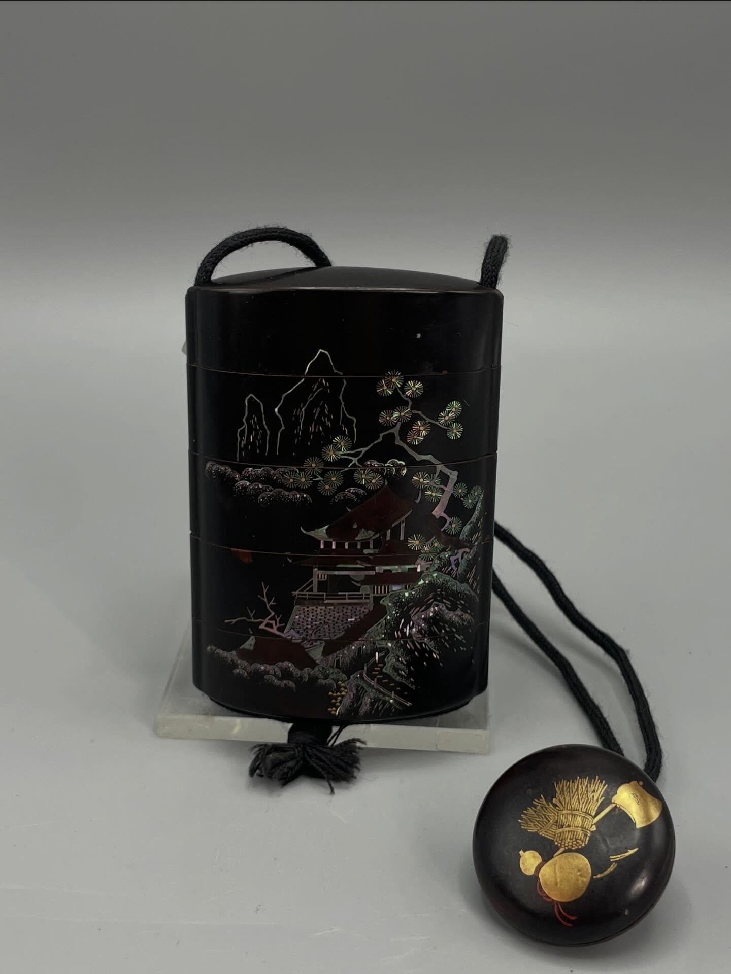 Ancient Japanese inrō in black lacquer, composed of several compartments.
One side is decorated with a traditional Japanese landscape featuring a pavilion, mountains, and stylized vegetation, enhanced with gilded details and mother-of-pearl inlays.
The other side displays a calligraphic design with vertically arranged gilt Japanese characters, accompanied by seals, in imitation of a literati inscription.
The interior is lacquered in gold. Retains its original cord and a decorative netsuke.
A fine example of Japanese art, reflecting the refinement and craftsmanship of traditional lacquer work. #inro #japan #japanart #laque #japon