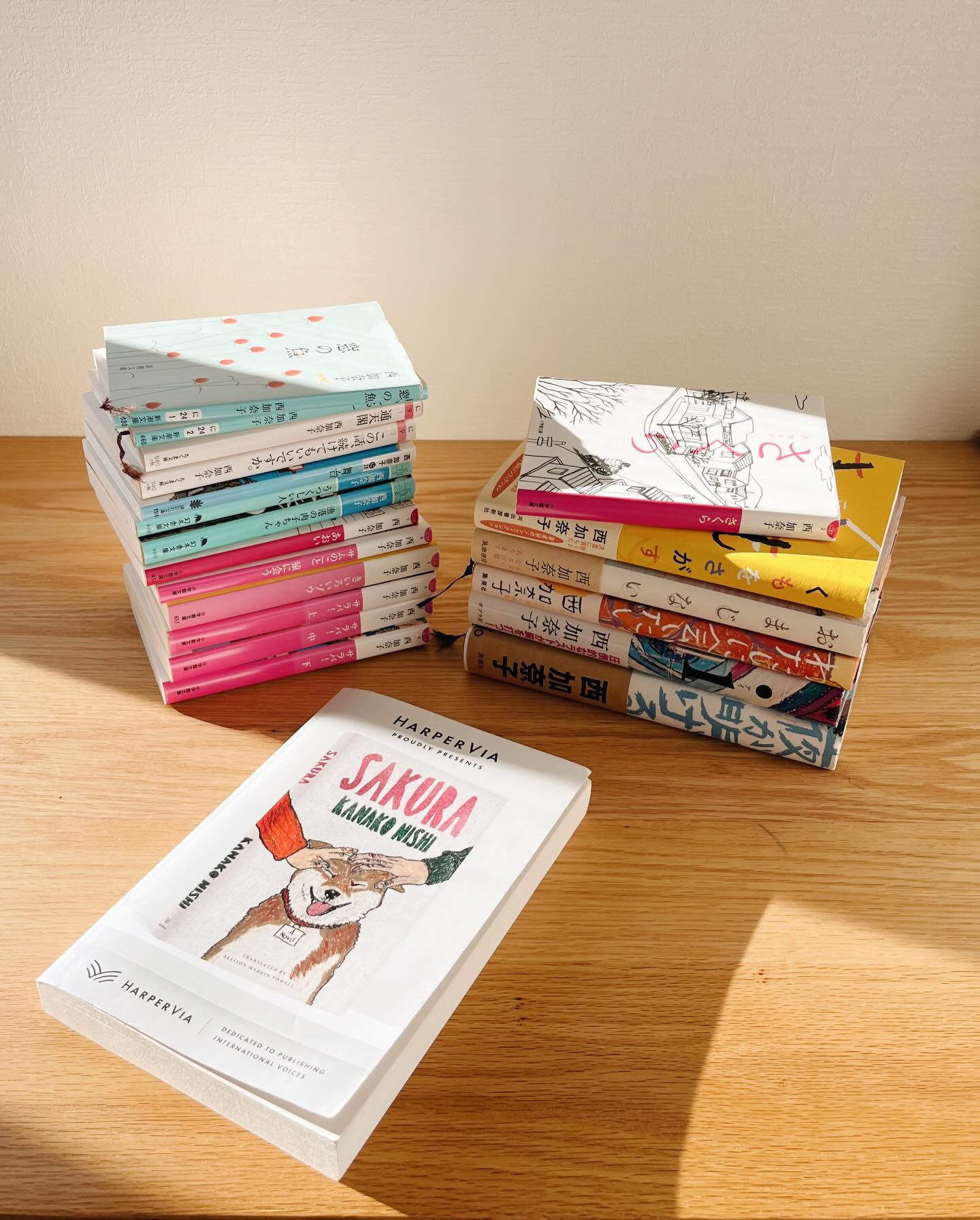 A little look at my Kanako Nishi collection…as you can see, if she writes a book, I will buy it.
She’s one of very few authors that I will go outside, rain, sleet, snow, on pub day to buy whatever she’s publishing.
Some of these books have moved with me over the years to different dorms, apartments, houses in different cities, prefectures, states, countries.
Which is why I am thrilled that one of these gems is being published in English! This March! In a brand new translation by Allison Markin Powell! Thank you to Allison and @harperviabooks for a copy of the book I’ve been screaming to hold in my hands.
As you can see from the stacks of books here, Kanako has written prolifically over the years - novels, short story collections, and essays since 2007 - all brilliant, ALIVE, pulsing with an inimitable energy and life force, and the one you get to read first is SAKURA, one of the first novels she wrote that made people stop and take notice.
Published in Japan in 2007, I’ve read the novel in Japanese over & over, watched the film, am doing a 2026 reread, and can’t wait to tell you all about it in English. A full description coming soon ⭐️
After I retrieved all of her books from my shelves, took photos, then put away all her books, I remembered the 2020 issue of the Japanese magazine EUREKA, which devoted an entire volume to the author. (Second photo)
I pulled out the magazine and started leafing through it…and here I go, down the Kanako Nishi rabbit hole for the umpteenth time…
She does that to you.
SAKURA is coming March 2026! (You will hear more from me about this author 💓)
- - -
西加奈子さんの作品というものは、一冊を読み始めると全て読み返したくなる。何度読んでも読み返したくなるし、その度初めての出会いのような衝撃が走る。自分の中の変化に気づかされるからなのかもしれない。物語の沁み方が、囁き方が、包み方が変わっていることに気づく。ハッと。それが去年出版されたばかりの本だとしてもそう。それはもう、呼吸が聞こえてくるとしか…
今日、西さんの本をまた並べてみようと思った理由は、今年3月にアメリカで、ずぅーっっっと待っていた西加奈子先生の『SAKURA』の英訳が出版されるからです。翻訳はアリソン・マーキン・パウエルさん!おふたりの間にどのようなケミストリーが起きるのか、楽しみすぎて心臓バクバクです。
西加奈子さんの作品を本棚から出してきて、写真を撮って、本棚に全てしまった後、「あ、あれも!」と文芸誌の棚から取り出した「ユリイカ」の西加奈子特集(2枚目)。2020年11月に出版されたこちらの雑誌を今読み返すと、世界の中と外、私の中と外で変わったことがありすぎて少しクラクラするけれど、西加奈子さんの作品を読んでもらう「生きる」だけは変わらなくて安心した。ちょっとグラグラっときそうな時に。私は西さんの作品に戻る。
3月が待ち遠しい。