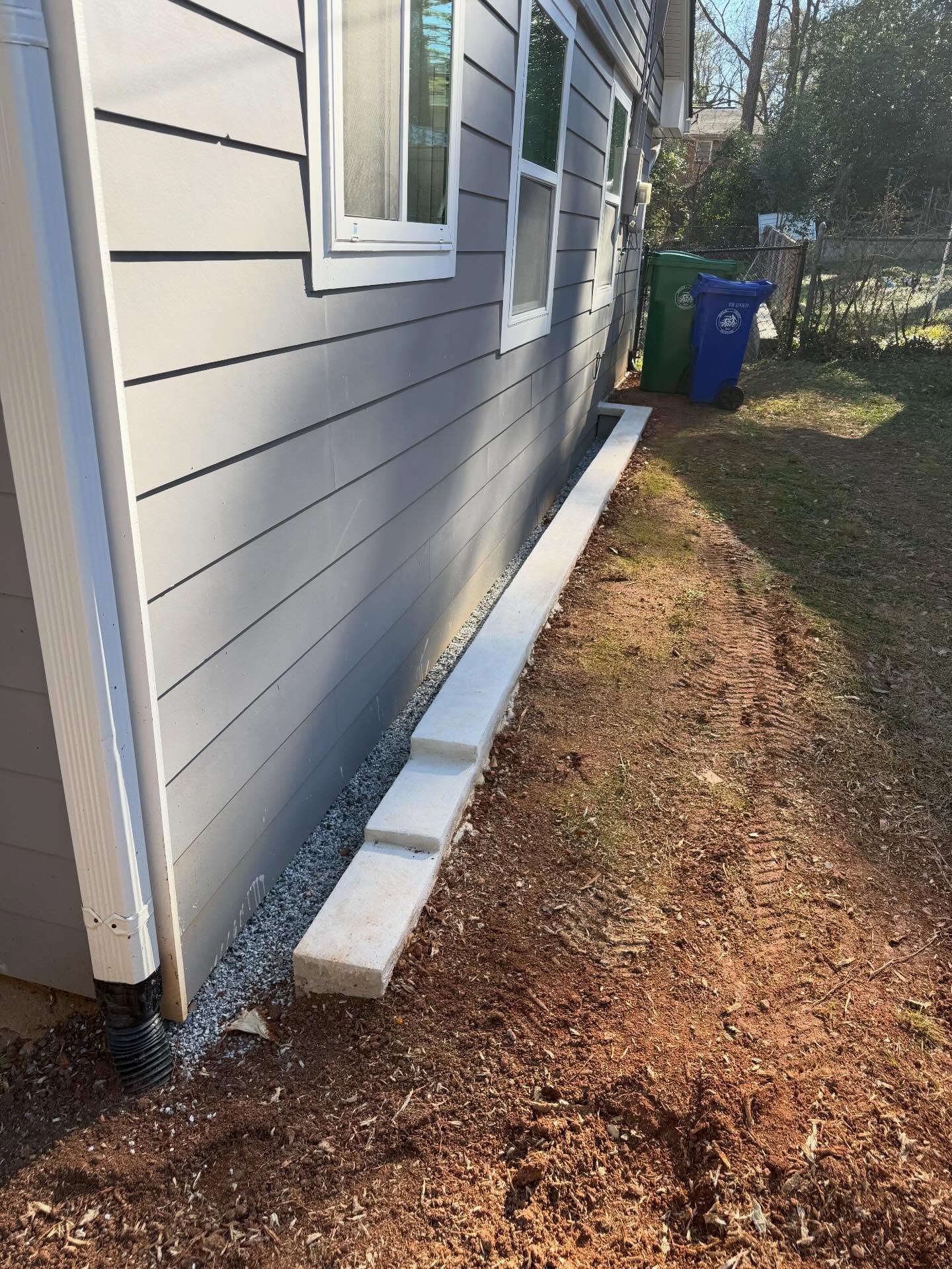 This is what we call a moat. This solution is used when exterior grade is touching a framed wall or the grade is allowing water to come in at basement/crawlspace doors. This keeps the solution simple and isolated. Between the moat and the framed structure, we install a French drain with a rubber membrane in the trench to manage any water that may land in that space during heavy rain events.