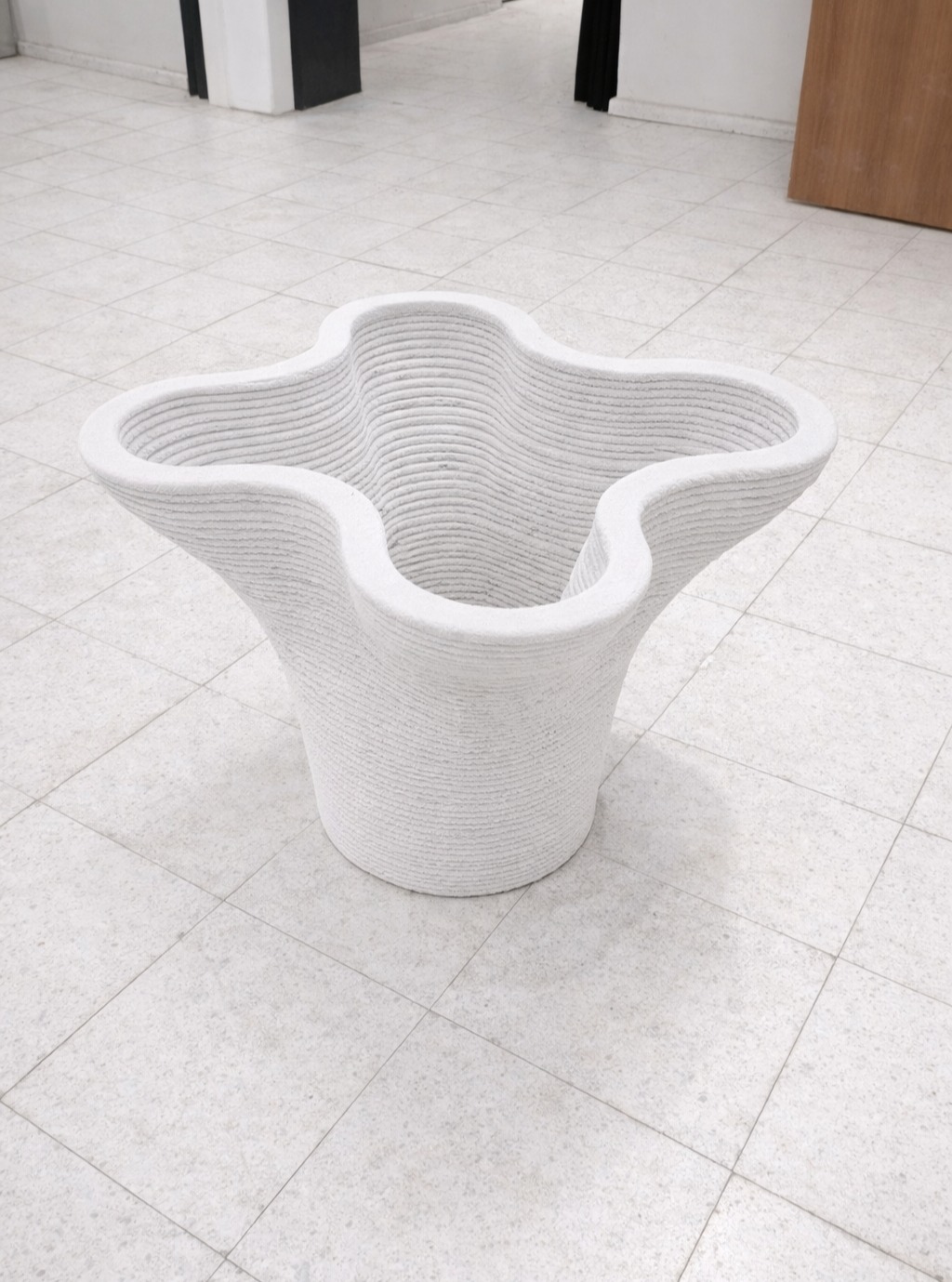 A freestanding multi-lobed vessel with a smooth vertical profile.
The geometry expands outward from a compact base
into a soft, rounded upper form,
defined by continuous curvature and uniform layering.
The surface shows consistent layer lines,
resulting in a clean, repetitive texture
across the entire height.
#3dconcreteprinting
#freeformgeometry
#layeredmanufacturing
#concreteobject
#roboticfabrication
#digitalconstruction