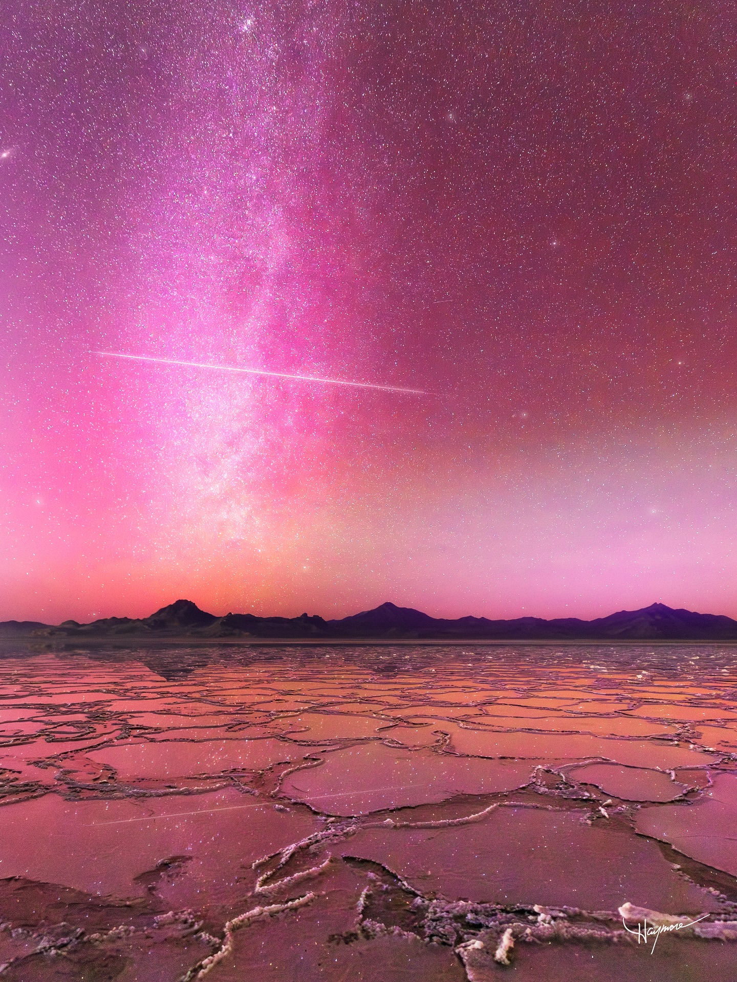 A whirlwind of events and emotions. I was in Death Valley spending a few days exploring remote backcountry dune fields when news spread of a massive solar storm rapidly approaching Earth. We quickly packed up and drove across Nevada to arrive at Utah’s flooded salt flats by 7pm.
As we were photographing the Aurora, I was looking down helping another photographer with her settings when suddenly, everyone started shouting…..a massive meteor had just streaked half way across the sky, right in front of the Milky Way!
I completely missed it. Feeling super bummed, I then looked over at my camera, which was taking 15 second exposures. The last photo taken then displayed on the screen…..the meteor was captured!!! While everyone around only saw it with their own eyes, I was the only one to capture it on camera. What luck!!
I was beyond thrilled to catch it on top of the incredible pink Aurora reflecting over the salt flats! That was the cherry to top off an amazing trip to Death Valley and back home.