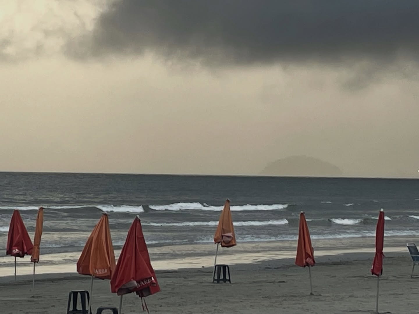 Quando o Céu Pesa sobre as Ondas
Guarda-sóis recolhidos como asas cansadas,
banquinhos vazios à espera de ninguém—
a praia respira sozinha
sob nuvens de chumbo e espuma.
O mar não descansa:
trança rendas brancas na areia,
sussurra segredos antigos
que o vento dispersa antes de chegarem.
Entre o céu pesado e o mar inquieto,
a praia se faz intervalo,
linha tênue onde o mundo hesita
entre explodir ou adormecer.
E nós, pequenos observadores,
medimos com os olhos
a distância entre a tormenta e a calmaria,
sabendo que ambas, no fim, são uma só.
#poesia #fotografia #photographer