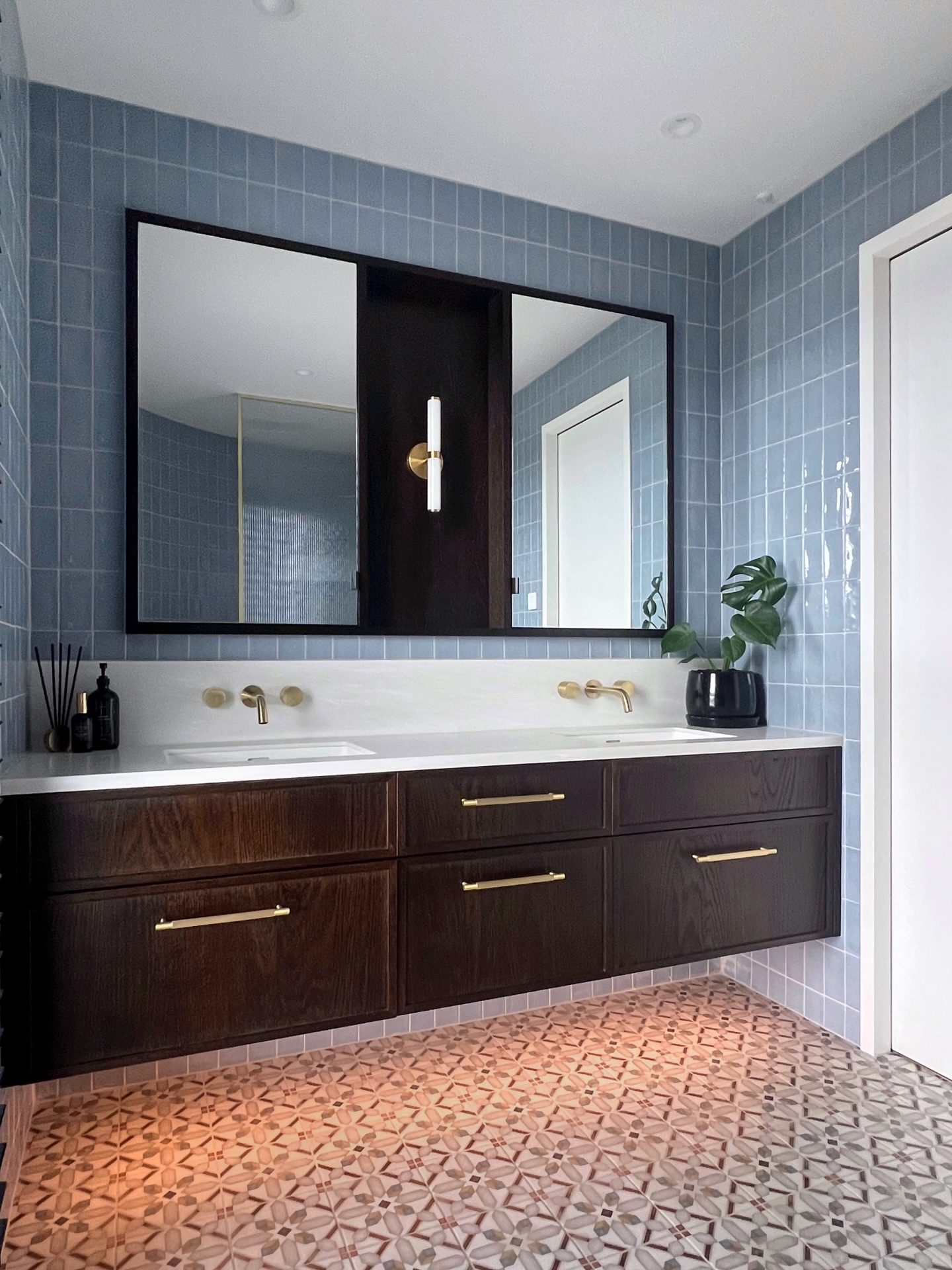 Curves, colour and personality - reflecting our client’s style ✨
Smoky blue tiles, warm timber joinery and brushed brass details set the tone in this ensuite.
The tile wrapped curved wall leading into the shower creates flow and softens the space, while the patterned floor tiles add a touch of character.