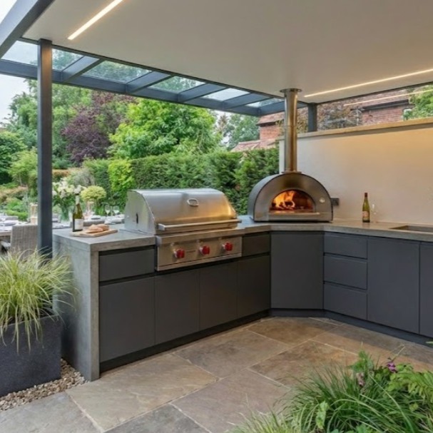 A long standing client asked us to build him a contempary kitchen for his new home in York.
He had very specific requirements.
An outdoor/indoor kitchen. Open to the elements but also with a feel of indoor luxury.
We worked with a fabricator of bespoke metal pergolas and garden rooms to create the metal frame, and we built the wall (Which has a glass panel between the wall and the steel frame and then built a custom-made kitchen, including all doors, etc.
Thanks once again for sending the pictures in. We always like to see how our finished product looks years after the build was complete.