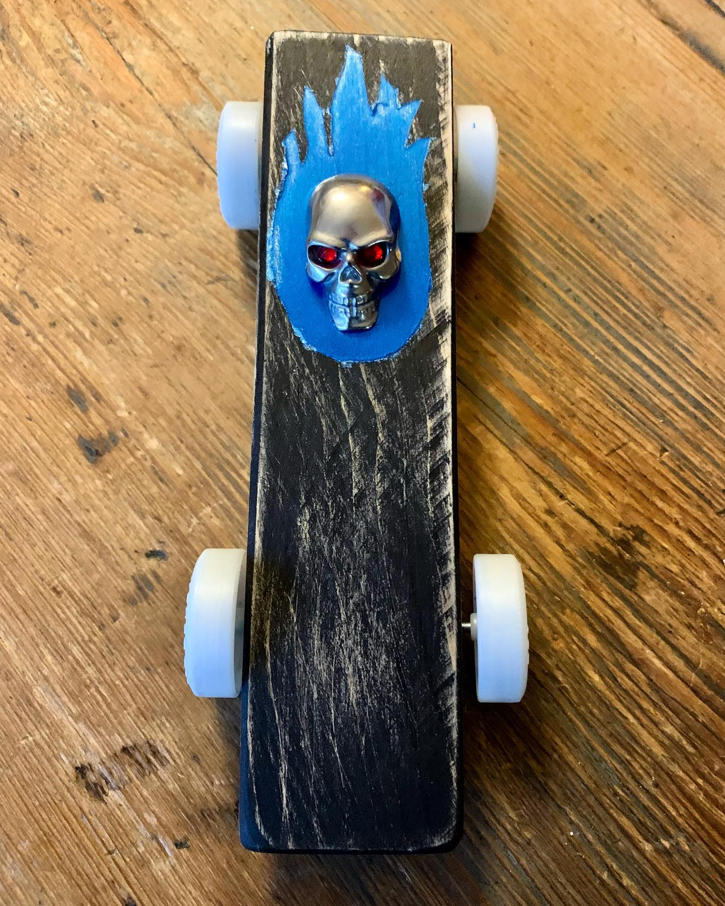The Haint Blue tribute Pinewood Derby Car by in house artist and resident third grader Thomas May. Featuring a distressed painted body, metallic blue flames, a tungsten steel skull and glow in the dark wheels. Inspired by Whisps and swamp gas we hope he places in the race!