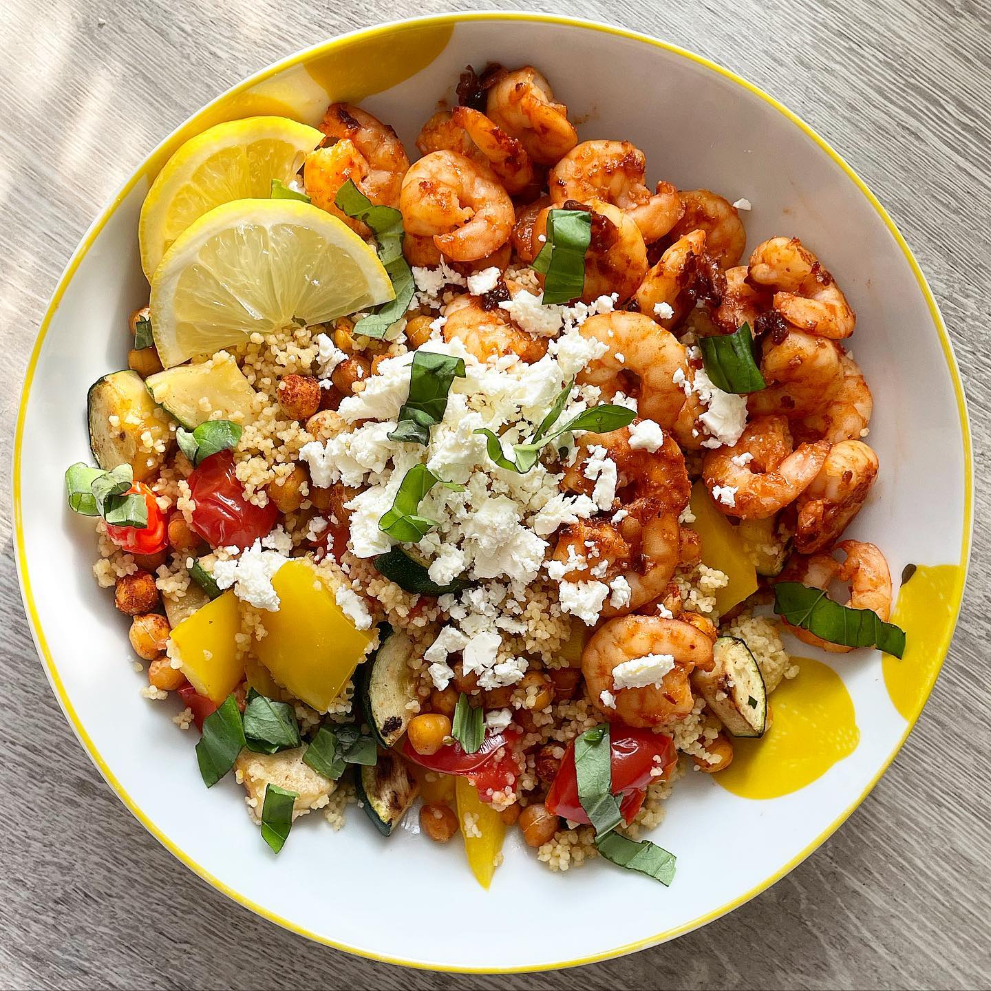 Mediterranean bliss 🌿 Sriracha prawns with roasted cous cous, peppers, tomatoes, courgette and chickpeas, topped with feta, basil and lemon ☀️