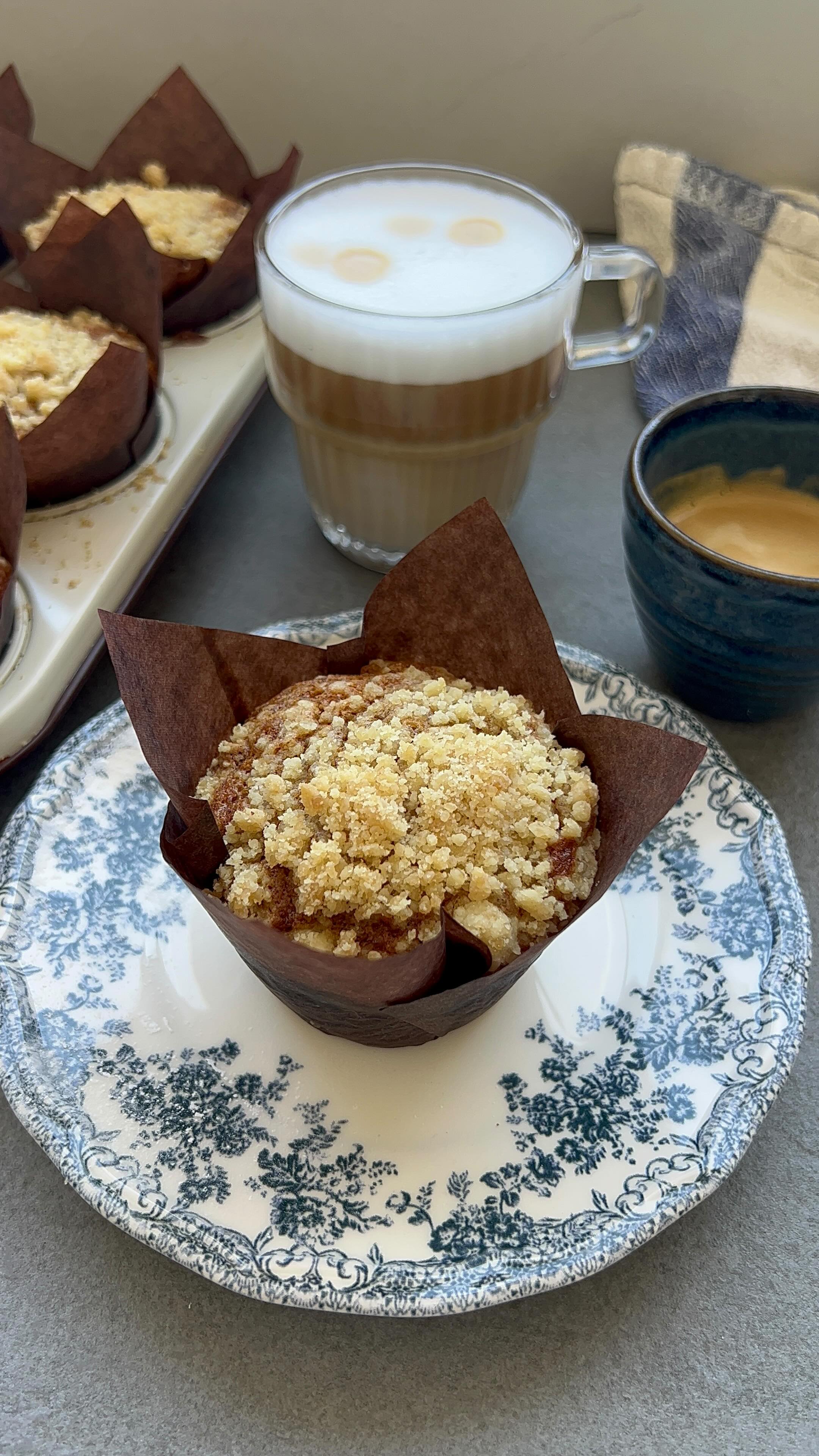  מאפינס
גזר פירורים ומתכון של לגזור ולשמור
מאפינס גזר רכים ועסיסיים עם פירורים,המאפינס אווריריים, נימוחים ועסיסיים בטירוף
.החלפתי חצי מכמות השמן ביוגורט יווני, מה שנותן רכות מושלמת, לחות שנשמרת ואיזון טעמים מדויק. הפירורים הפריכים מעל מוסיפים קראנץ׳,וציפוי היוגורט וניל בציפוי חלומי.
אני מכינה כמות, מקפיאה, וכשמתחשק שולפת אחד, מחממת
פינוק מושלם לצד הקפה.
בשיתוף דנונה
למתכון:
130 גרם סוכר לבן (¾ כוס + כף)
40 גרם סוכר דמררה (¼ כוס)
2 ביצים L בטמפרטורת חדר
70 גרם יוגורט יווני דנונה (חצי מכל)
80 מ״ל שמן (1/3 כוס)
2 גזרים גדולים מגוררים דק (150 גרם)
40 גרם אגוזי פקאן טבעיים קלויים קצוצים (⅓ כוס)
105 גרם קמח לבן או כוסמין (¾ כוס)
1 כפית קינמון
1 כפית אבקת אפייה
חצי כפית סודה לשתייה
קורט מלח
אופציה לשדרוג (כפית גרידת תפוז)
לפירורים:
4 כפות קמח
2 כפות סוכר חום דמררה
30 גרם חמאה קרה חתוכה לקוביות קטנות
לציפוי יוגורט:
100 גרם יוגורט יווני
רבע כפית מחית וניל
4 כפות אבקת סוכר
אופן הכנה:
מחממים תנור ל־170 מעלות טורבו.
מרפדים תבנית אינגליש קייק אחת או 9 שקעים של מאפינס.
בקערה גדולה טורפים היטב ביצים, סוכר לבן וסוכר דמררה עד שהתערובת מעט בהירה
מוסיפים שמן ויוגורט יווני וטורפים לאיחוד
מוסיפים גזר מגורר, אגוזי פקאן ואם משתמשים גרידת תפוז, ומערבבים
בקערה קטנה מערבבים קמח, קינמון, אבקת אפייה וסודה לשתייה
מוסיפים את היבשים לקערה עם הרטובים ומערבבים רק עד איחוד, בלי לערבב יתר על המידה.
לפירורים:
בקערה קטנה שמים קמח, סוכר דמררה וחמאה קרה
מועכים עם האצבעות עד שמתקבלים פירורים דקים
מעבירים את הבלילה לתבנית אינגליש קייק או מחלקים ל9 מאפינס.
מפזרים מעל פירורים בנדיבות.
אופים
מאפינס :20–25 דקות
אינגליש קייק :40–45 דקות
עד שקיסם יוצא עם פירורים לחים
תלוי בעוצמת התנור חשוב לבדוק אחרי 20 דקות אפיה.
מצננים לחלוטין.
ציפוי יוגורט
מערבבים יוגורט יווני, מחית וניל ואבקת סוכר עד לציפוי חלק
מורחים מעל המאפינס או העוגה.
הציפוי מתייצב אחרי קירור.