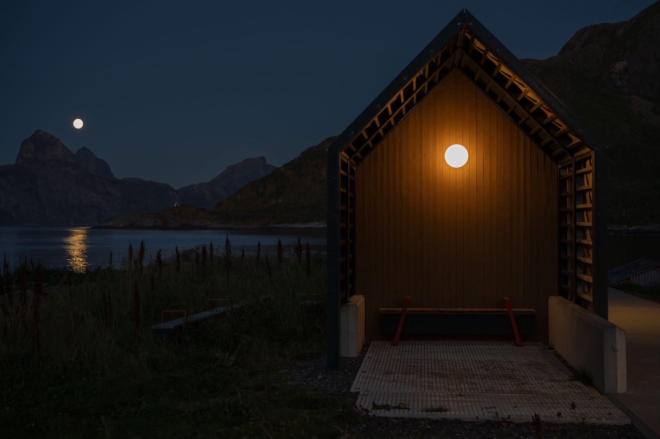 On Senja, even the most functional buildings feel considered. They don’t compete with the landscape, they pause within it. I noticed the small public building in Mefjordvær late in the evening as I was shooting the full moon over Segla. As the light faded, its presence became clearer rather than disappearing.
Warm light spilled softly onto the ground, while a single round lamp echoed the moon above the fjord. Restraint, geometry, and atmosphere, everything felt intentional.
Architecture images shot with Sigma‘s amazing 50mm f/1.2 prim lens wide open. Full moon over Segla was shot with Sigma 100-400mm lens.