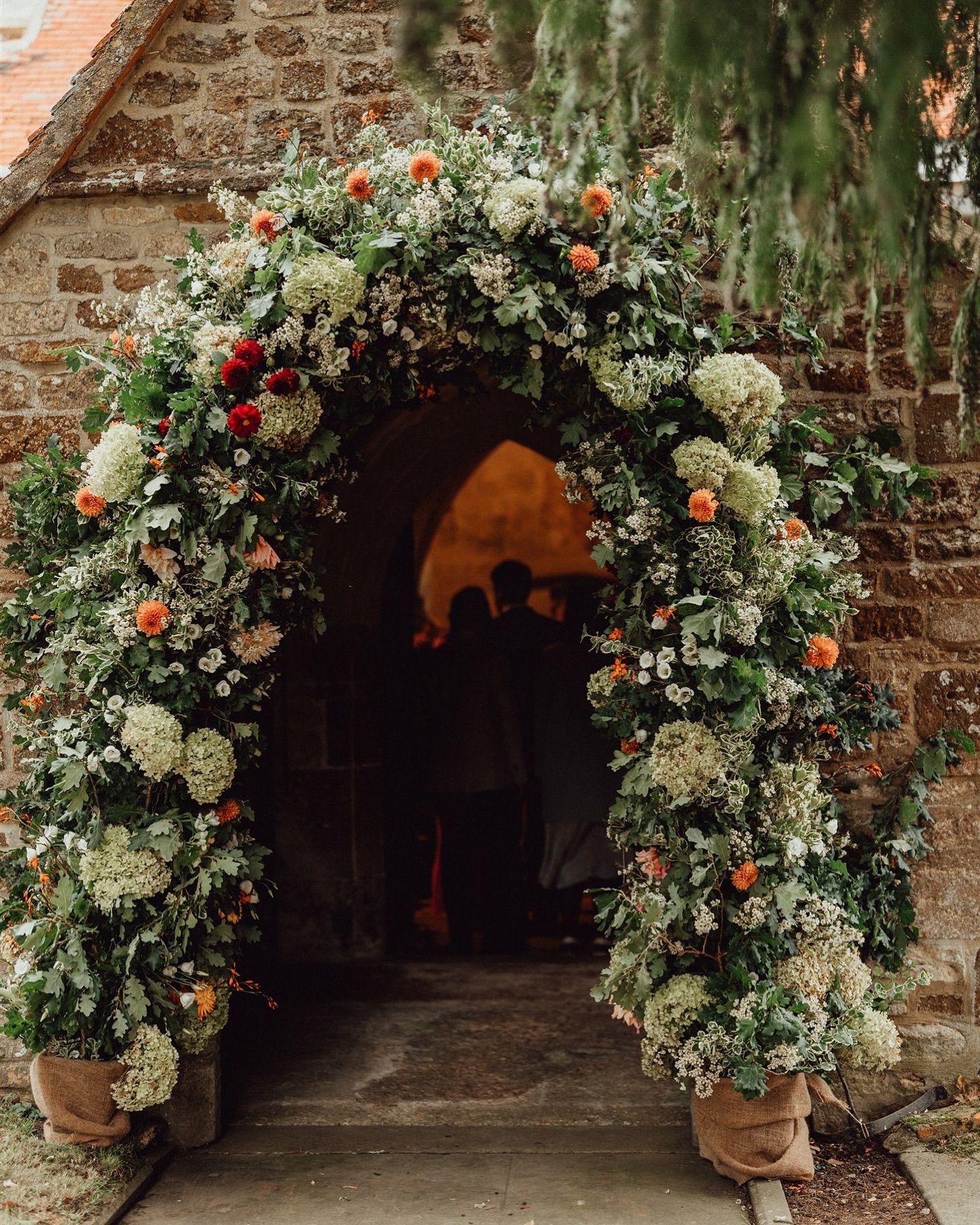A WARM WELCOME is what this picture says to me.
I’m currently reviewing notes, the set-up we did today, and what’s left to complete in the morning. R&R’s celebration tomorrow has all the right ingredients for a truly warm, relaxed, Christmas-time wedding.
But what is it, really, that brings the warmth and joy to a wedding day? The people, naturally. Your guests play an enormous part in how your wedding feels. But setting a scene, and nudging people in the right direction, goes a long way too. Like this church entrance, for M&W last September. An entrance that says come in, light and laughter awaits.
Photographer: @emilystevephoto
Florist: @pmheumann
Stationery: @moocoxfordillustrations
#churchflowers #weddingarch #flowerarch #northamptonshirewedding #weddingplanneroxfordshire
🗝️ Karin Tindall is an Oxfordshire-based wedding planner, offering full wedding planning and on the day coordination