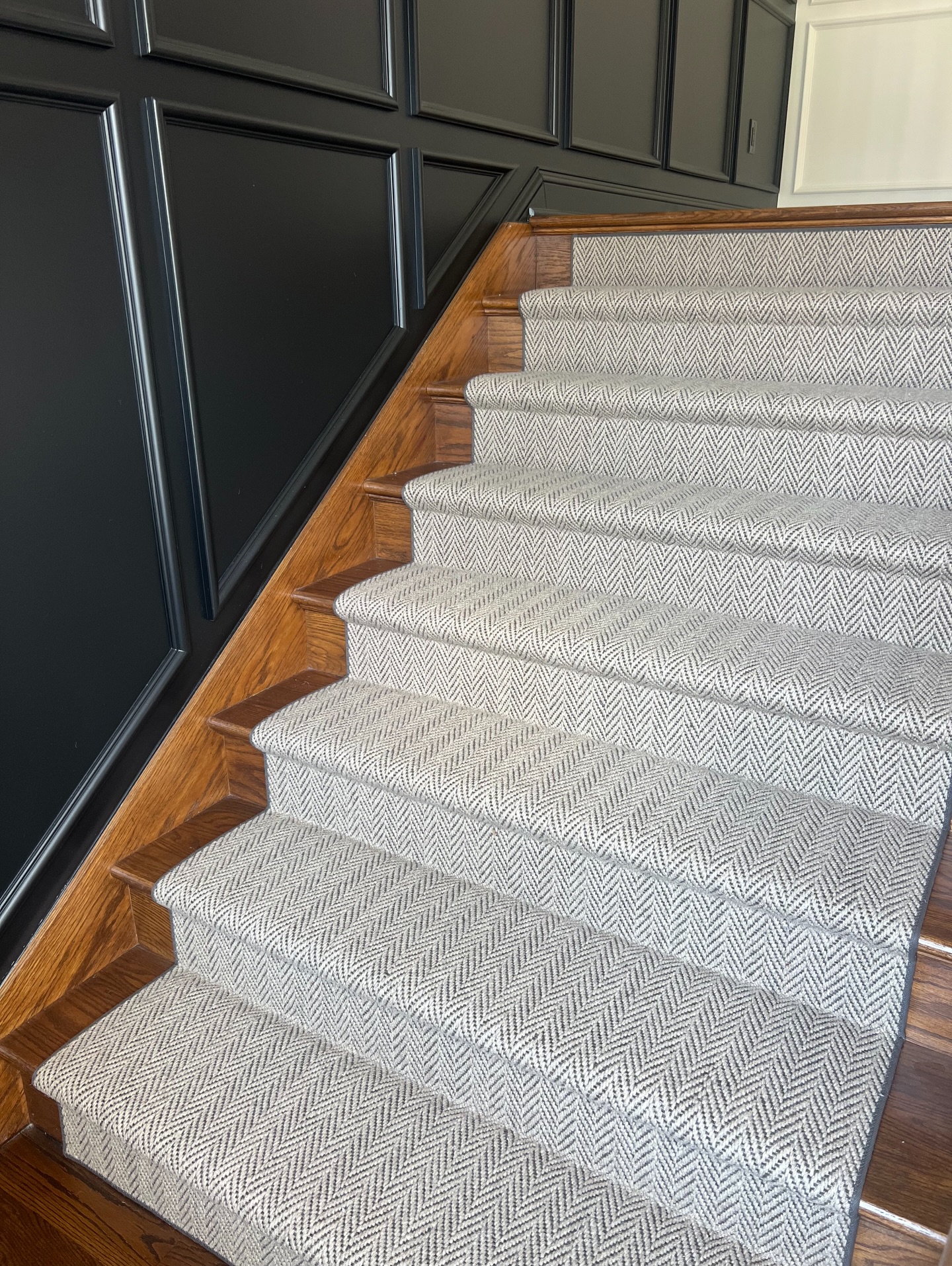 Our timeless wool herringbone stair runner gracefully climbs two full flights, adding warmth, texture, and quiet luxury to every step. Paired with rich wood tones and classic millwork, beautifully designed by @stagingspacesdesign. #TimelessDesign #WoolRunner #StairRunner #PrestigeProjects #SimplyQuartered