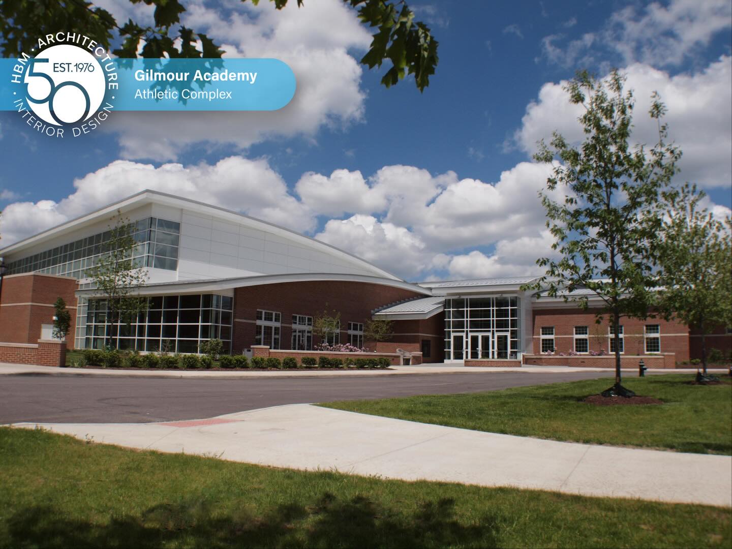 HBM’s relationship with Gilmour Academy spans decades, with projects that have shaped and supported the evolution of the campus over time. In 2010, that ongoing partnership led to one of its most transformative additions: the new 78,000-square-foot Athletic Complex.
The project replaced an aging 1950s gymnasium and natatorium that no longer met the needs of a growing athletic program. The new 17,000 SF arena-style gym and 12,000 SF natatorium provide updated facilities designed to support increased participation, competition, and spectator capacity.
Heritage Hall serves as the central connector, linking the facility’s main components. It functions as both a gathering space and a showcase for the school’s academic and athletic history. Extensive interior glazing provides transparency, making activity visible from almost any location.
The facility features advanced systems that enhance performance and efficiency, such as rim-flow pool gutters, ultraviolet water filtration, heat recovery, fabric ductwork for humidity control, and integrated technology for live streaming and digital displays.
The result is a modern athletic center that feels connected to its historic campus while providing students with a facility built for participation, competition, and community.
#HBM50 #Architecture #Design