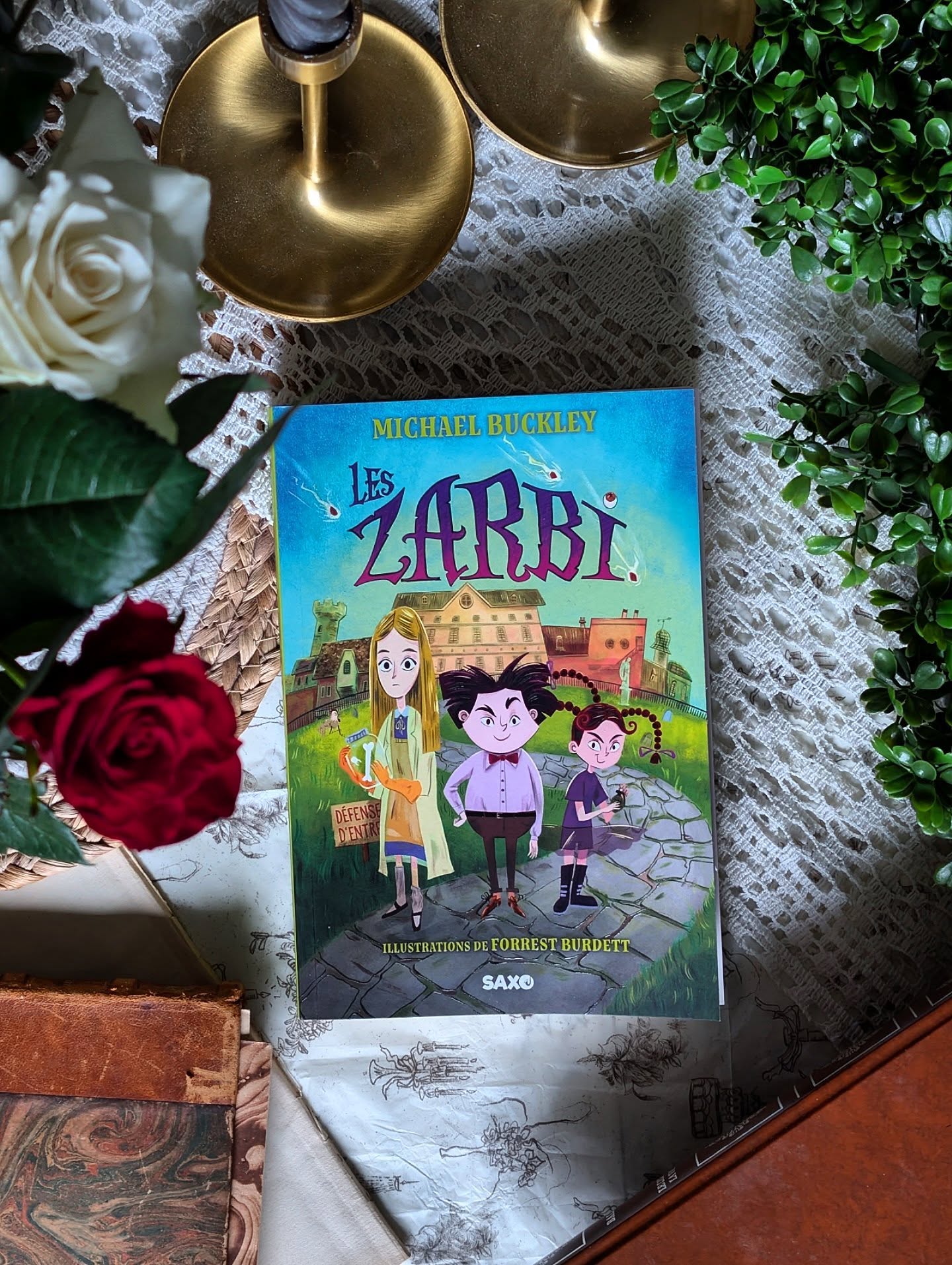 ✨ Les Zarbi - Michael Buckley ✨
Quelle belle surprise fut cette lecture !
Je m'attendais au vu de la couverture à quelque chose d'assez enfantin, mais non ! En vérité je n'ai jamais été déçu des romans de chez @editions_saxo même quand ils sont étiquetés jeunesse.
On tient ici un roman dans la vibe de « Les Désastreuses Aventures des orphelins Baudelaire », alors si vous avez aimé cette histoire, vous allez sûrement adoré aussi celle-ci.
À travers une narratrice pleine de sarcasme et d'humour, on fait la connaissance de la famille Zarbi et plus particulièrement les triplés : Bernache, Mélancolie et Échalote. L'une est fascinée par le corps humain, l'autre adore les bosses sur les crânes et la dernière aime allumer des feux.
Un matin, ils se réveillent dans leur immense manoir… complètement vide. Leurs parents ont disparu. Officiellement ils sont partis en vacances et ça aurait mal tourné. Mais est-ce vraiment toute l’histoire ?
Expédiés dans un orphelinat, on va découvrir toutes les différences de ces enfants un peu... bizarres. Les Zarbi ne rentrent pas dans les cases. Ils ne comprennent pas les règles absurdes de la “normalité” et, honnêtement, ils n’ont pas très envie d’essayer.
C’est drôle et parfois absurde. Il y a plein de situations improbables et de dialogues savoureux. On sent l’amour de l'auteur (que je ne connaissais pas avant) pour les histoires un peu farfelues.
J’ai adoré suivre cette fratrie bancale mais ultra soudée. Ils ont toujours des idées farfelues et forcément, des catastrophes en découlent.
C’est le genre de lecture qui plaira autant aux enfants qu’aux adultes. C'est totalement atypique, alors foncez chez @saxo pour tomber vous aussi amoureux de cette histoire !
#LesZarbi #SaxoÉditions #roman #bookstagramfrance #MichaelBuckley