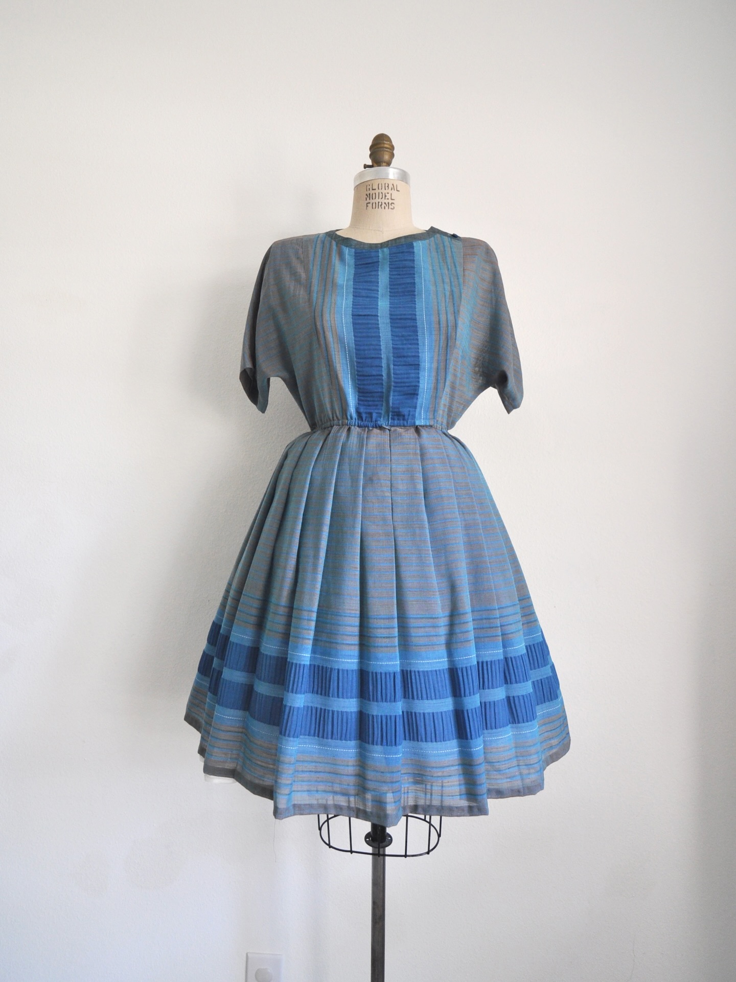 Link in bio to shop! 1980’s blue and gray striped dress. Feels like synthetic linen. Functional hidden buttons. Elastic waist. Pleated skirt. Bust: 36” Waist: 22-32” Length: 38” Shoulder to waist: 14.5”