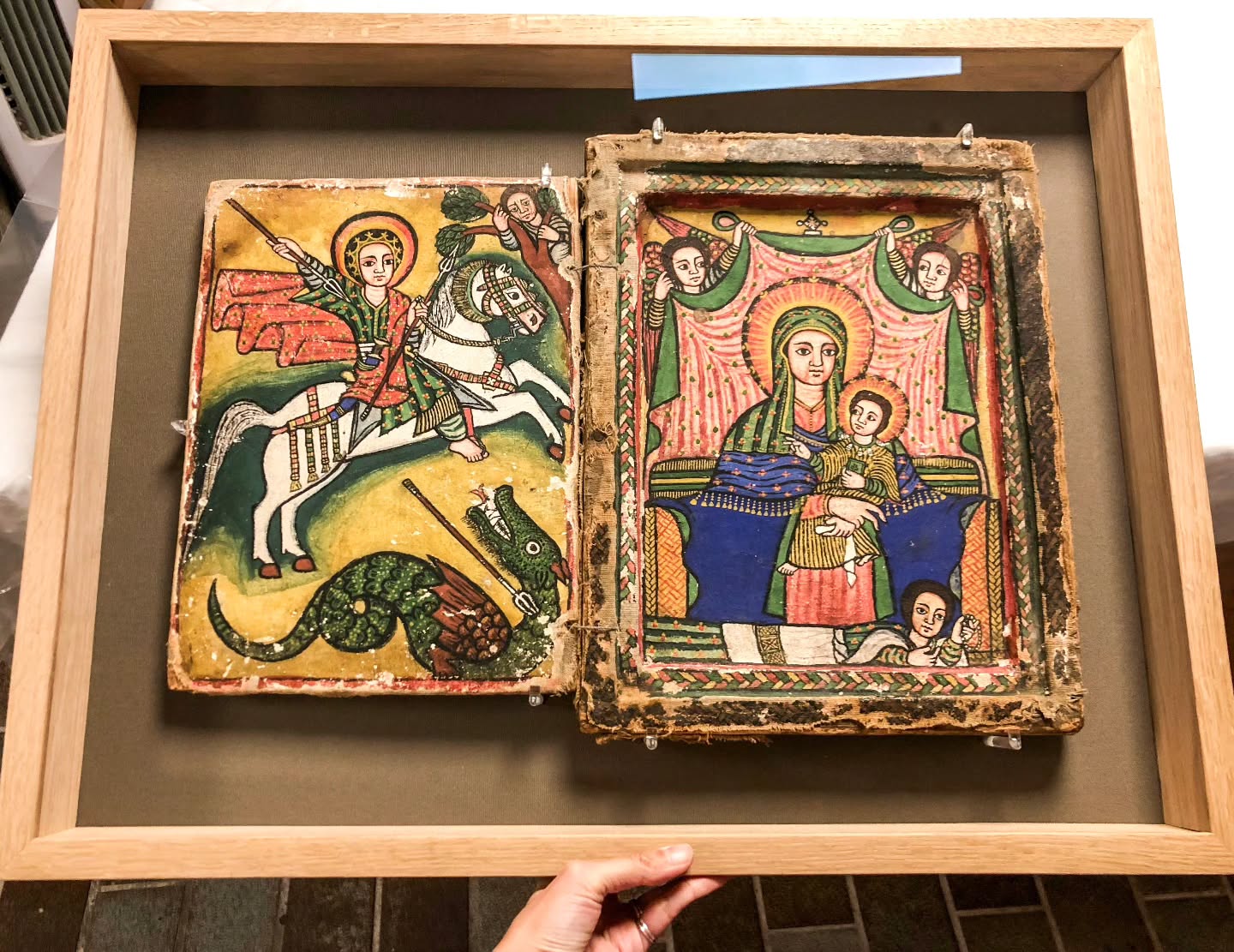 Encadrement technique, celui d'un diptyque d'icônes orthodoxes éthiopiennes représentant Saint George terrassant le dragon sur le panneau de gauche et la Vierge Marie avec l'enfant Jésus sur le panneau de droite.
Les éléments sont maintenu en place par des discrètes pièces en verre acrylique, montés derrière un verre de conservation premium.
🇬🇧 Technical framing of a diptych of Ethiopian Orthodox icons depicting Saint George slaying the dragon on the left panel and the Virgin Mary with the infant Jesus on the right panel.
The panels are held in place by discreet acrylic glass pieces, mounted behind premium conservation glass.
#encadrementdart #framyourart #framing #artframing #encadrement