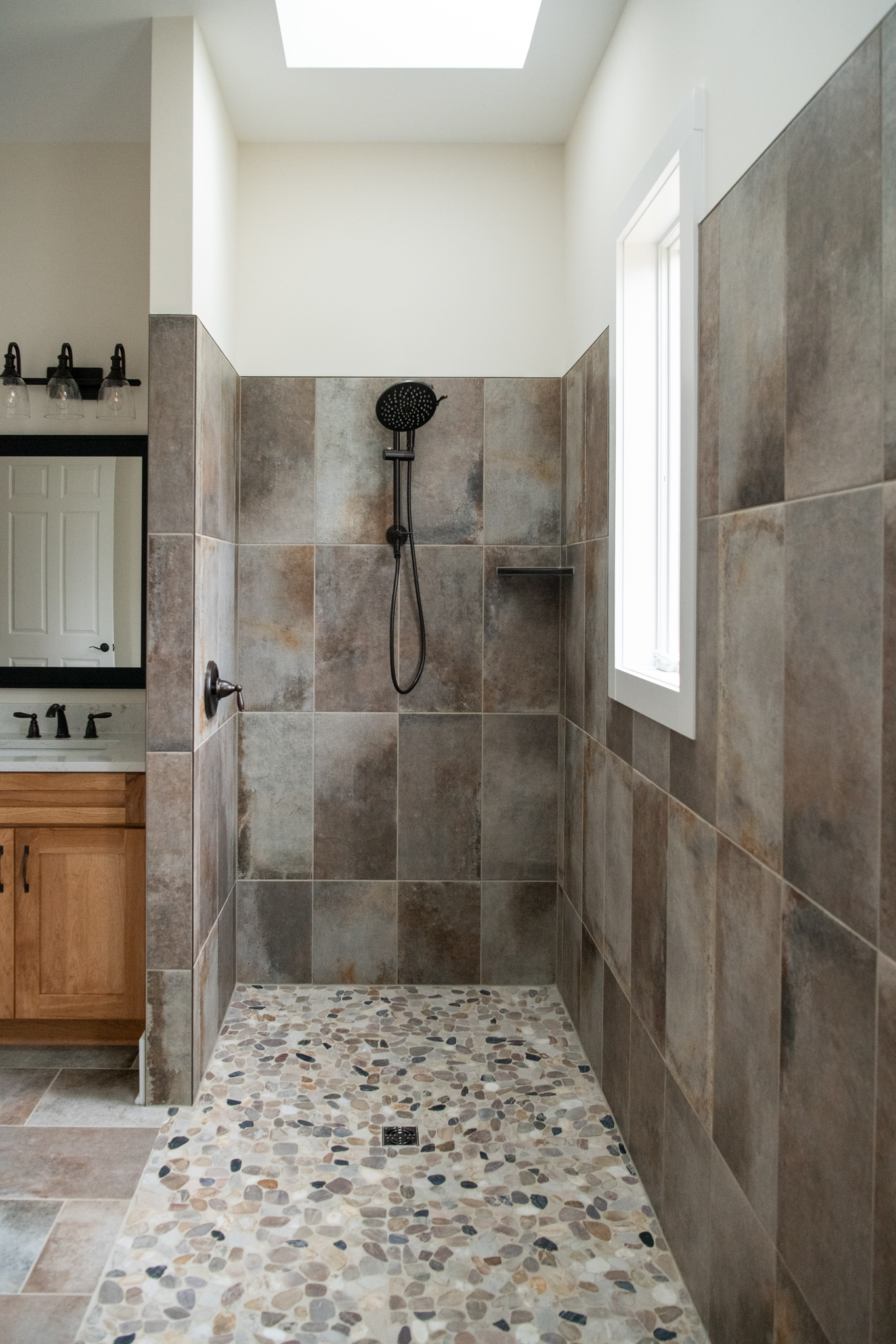 A walk‑in shower that feels like a natural retreat. The river-rock floor, warm tile, and skylight keep the home’s original character while creating a calming retreat you’ll want to linger in.