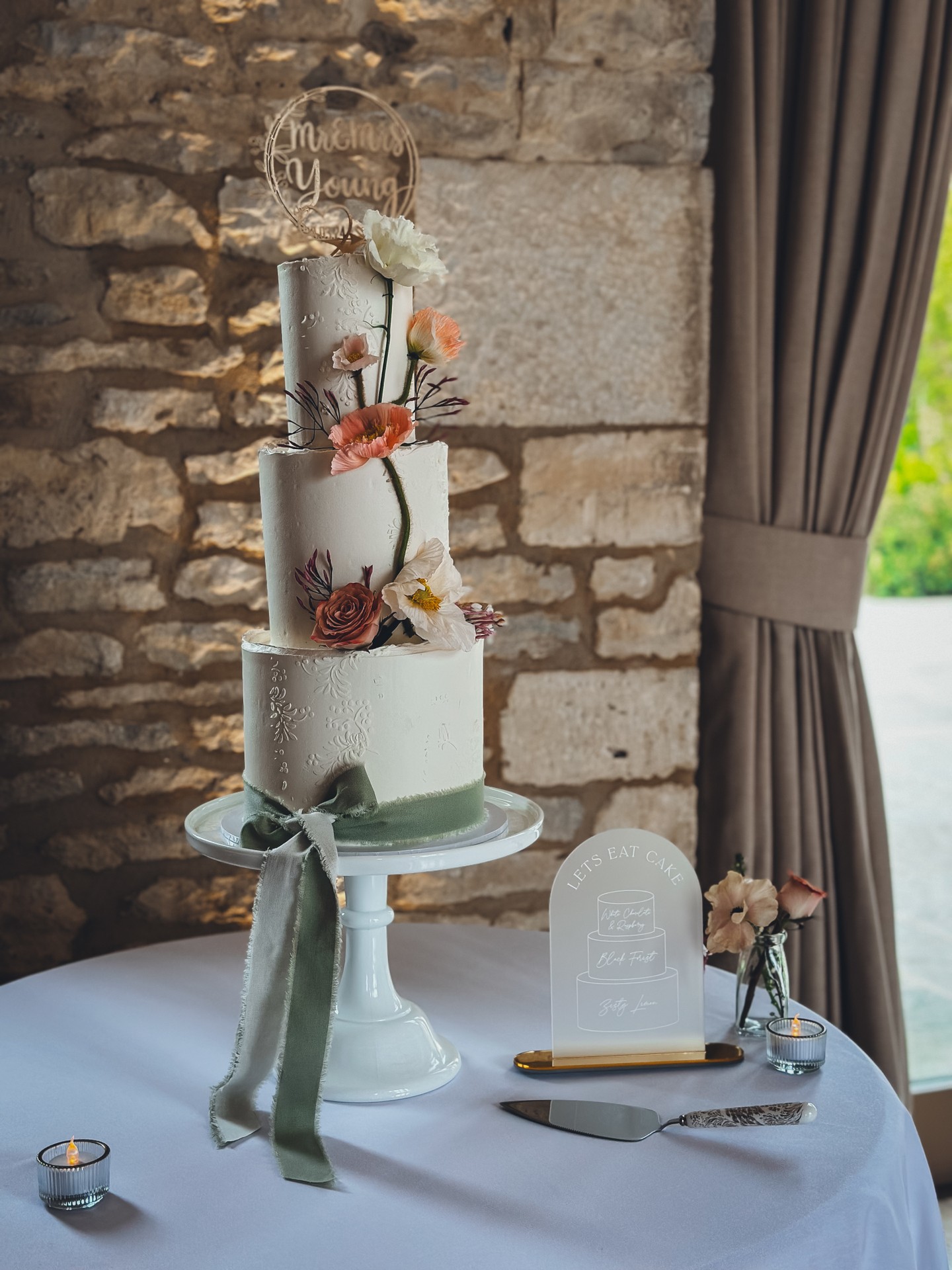 There is something about soft florals against textured stone that feels effortlessly romantic. 🤍🌿
Three tiers of ivory ganache, detailed with subtle embossed patterns and finished with delicate, climbing florals in muted peach, blush and warm terracotta tones.
The movement in the stems.
The softness of the petals.
The sage silk ribbon grounding the base.
Nothing feels forced. Everything feels placed with care.
This design was created to sit beautifully within a countryside setting, where texture, light and atmosphere all matter.
For couples who love organic details and understated elegance, this style allows the florals to lead while the structure remains timeless.
If you’re planning a wedding with a refined, romantic aesthetic, I would love to create something just as considered for you.
View the portfolio here:
https://www.kimberlyjaynecakedesign.co.uk/portfolio
Enquire via the website to check availability 🤍
#LuxuryWeddingCake #RomanticWeddingCake #FloralWeddingCake #CountrysideWedding #ElegantWeddingDesign