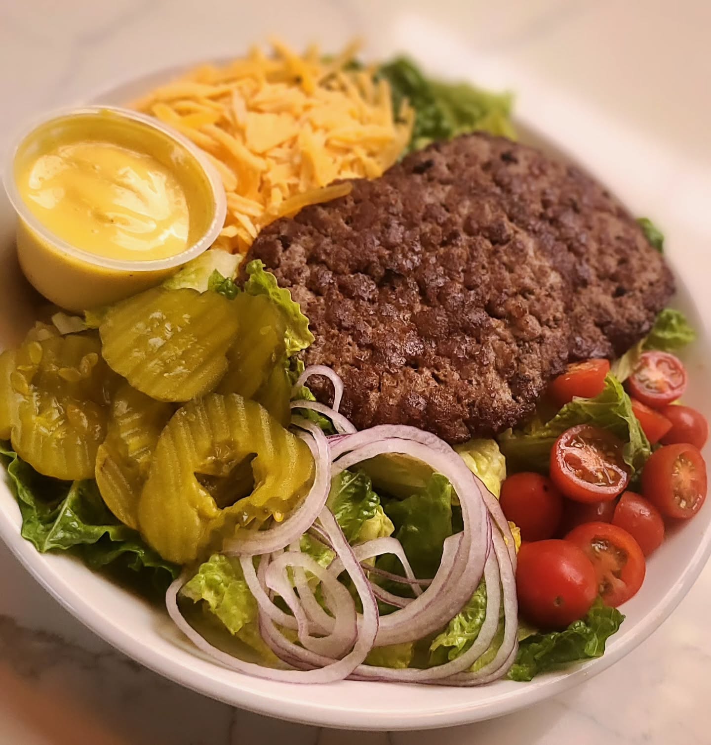 Cheeseburger Salad! Sounds silly but it's DELICIOUS! No more ordering your burger with no bun! We've cut out the nonsense AND the carbs for you! 2 Beef Patties, Cheddar Cheese, Pickles, Cherry Tomato, Red Onion, served with Honey Mustard Dressing. Order in-house or online!