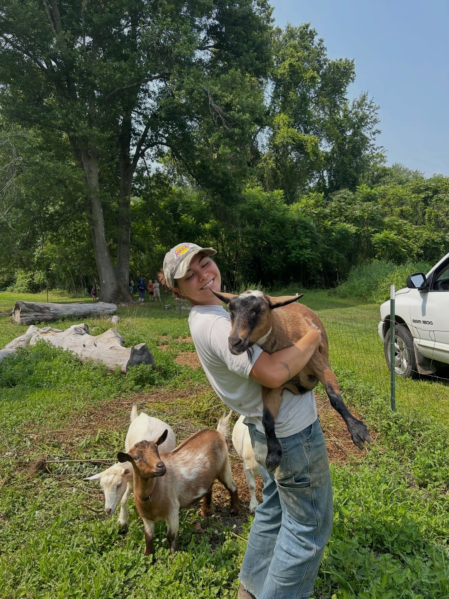 We 🤎 our goats. As we look forward to the CSA and Camp season, we are also looking forward to sunny days with the farms goats! In the first image you can see the campers in the background watching farmer Kaela lift one of the goats. In the second image you can see the goats being hand fed grapes 😂