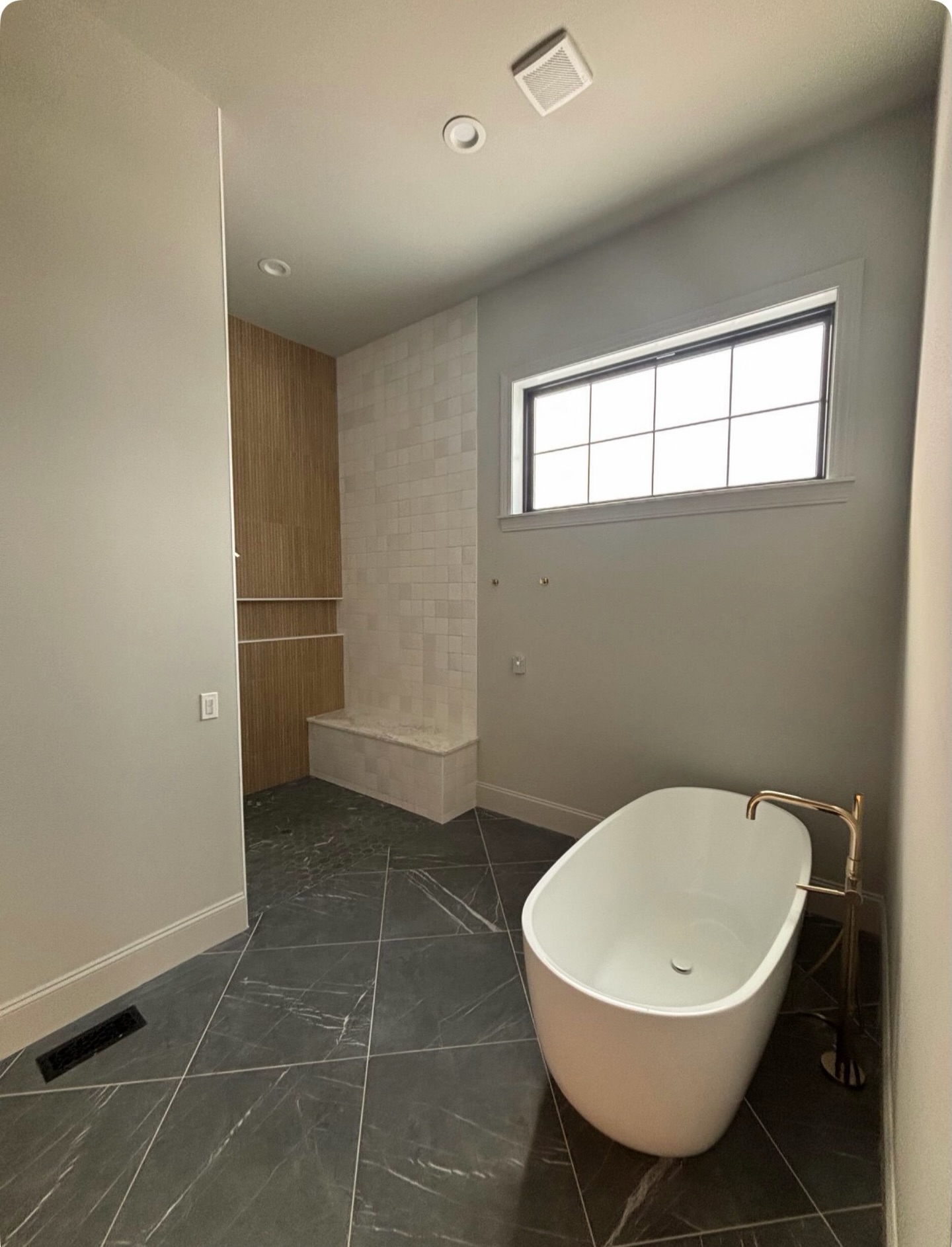 A dramatic large format tile underfoot with soft veining, a classic square tile climbing the shower wall, and a warm vertical wood-look tile that brings depth and contrast. Each material has its own voice, but together they speak the same timeless language. #TimelessFlooring #TimelessDesign #OldWorldCustomHomes #PrimaryBath #SimplyQuartered