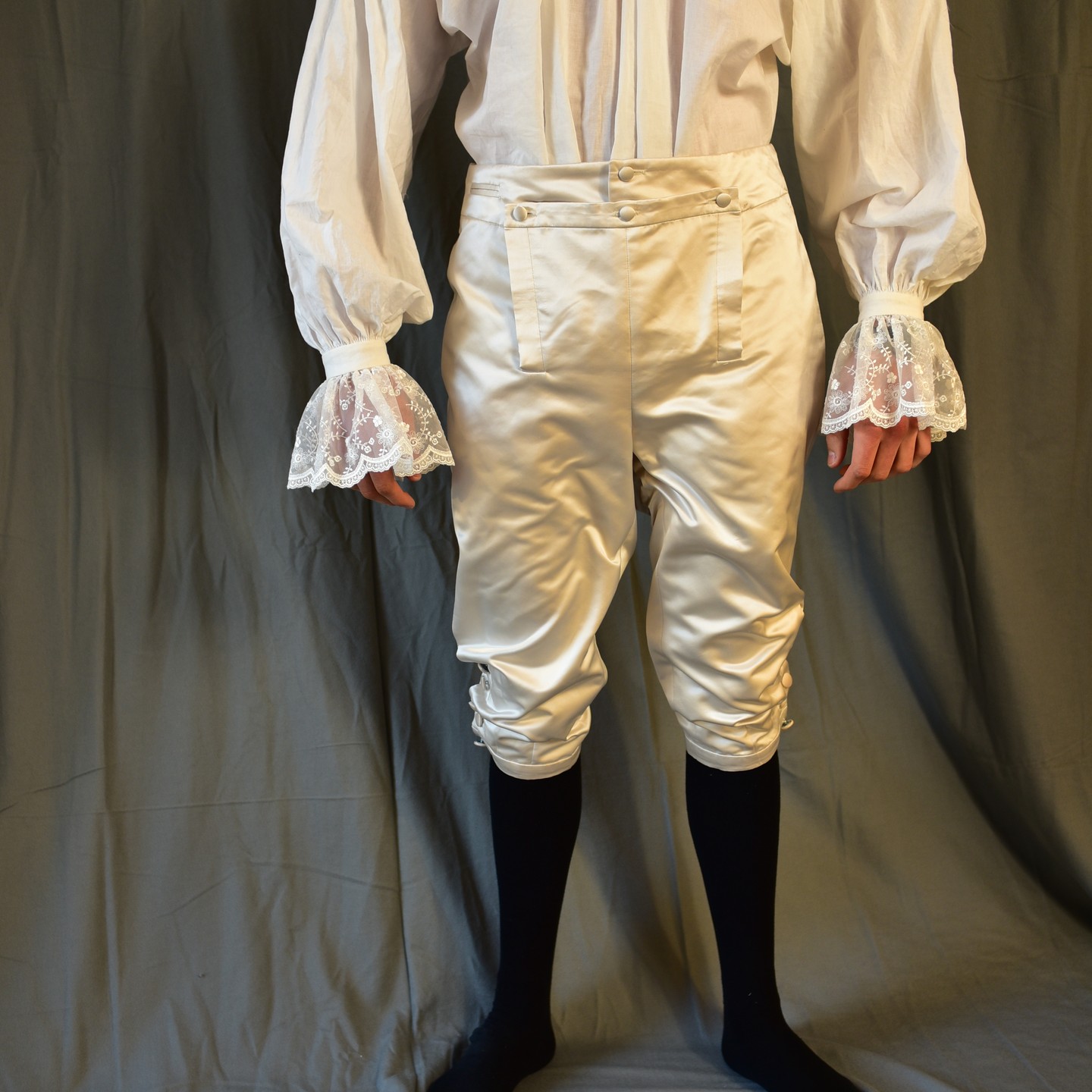 Diese culotte ist als Kniehose mit Latz und Uhrentasche gearbeitet.
Die überzogenen Knöpfe sind aus Seidenduchesse.