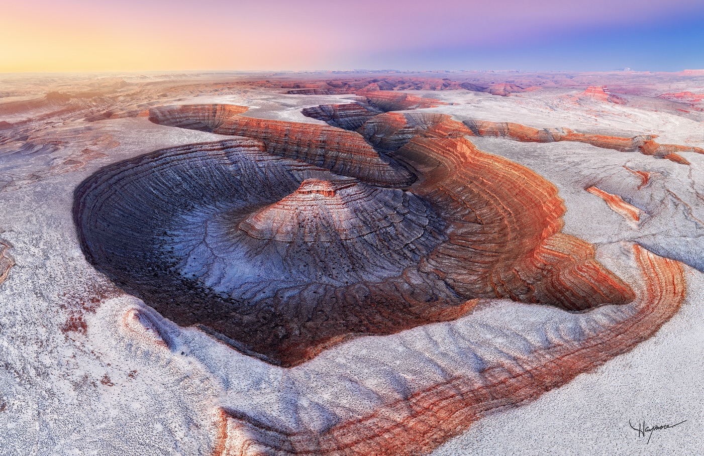 Heading back to base the night before after photographing sunset in the area, microbursts of snow squalls rolled in. The horizontal and swirling blizzard seemed to strike out of nowhere and made visibility difficult. We hoped for snow at this particular Rincon for sunrise.
As we drove in darkness pre-dawn, we saw hints of light snow dusting and crossed our fingers it was where we needed it to be. When we arrived, we were ecstatic to see snow blanketing the desert formations and highlighting the rims of canyons.
This image is a 9 photo panorama stitch to capture the enormous 180º scene. The warmth of the rising sun on the East transitioning to cold tones of’ the Belt of Venus’ to the West as the earth cast a shadow on itself was a delightful site to behold.
