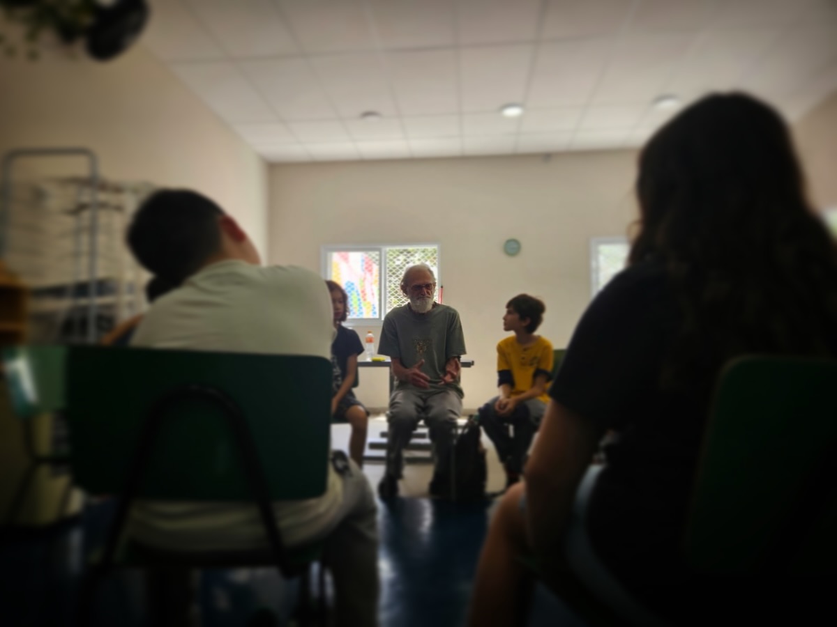 A riqueza de uma escola também mora nos encontros que ela provoca.
Há um tempo, recebemos na sala o Sr. Salvador, avô de um aluno, para compartilhar memórias da vida rural no Brasil dos anos 50. Uma infância simples, com outros ritmos, outras responsabilidades, outras formas de brincar e viver.
Mesmo sendo uma realidade distante da maioria das nossas crianças, a escuta foi atenta, curiosa e cheia de perguntas. O repertório construído nas leituras da sala, como Meu Pé de Laranja Lima, e as conversas frequentes sobre as histórias de cada família transformaram aquele momento em uma roda viva, sensível e cheia de significado.
Quando a comunidade entra na escola, o aprendizado ganha camadas.
As crianças ampliam o olhar, exercitam a empatia e compreendem que existem muitas formas de viver a infância.
Educar com respeito também é isso: abrir espaço para vozes, memórias e histórias que conectam gerações.