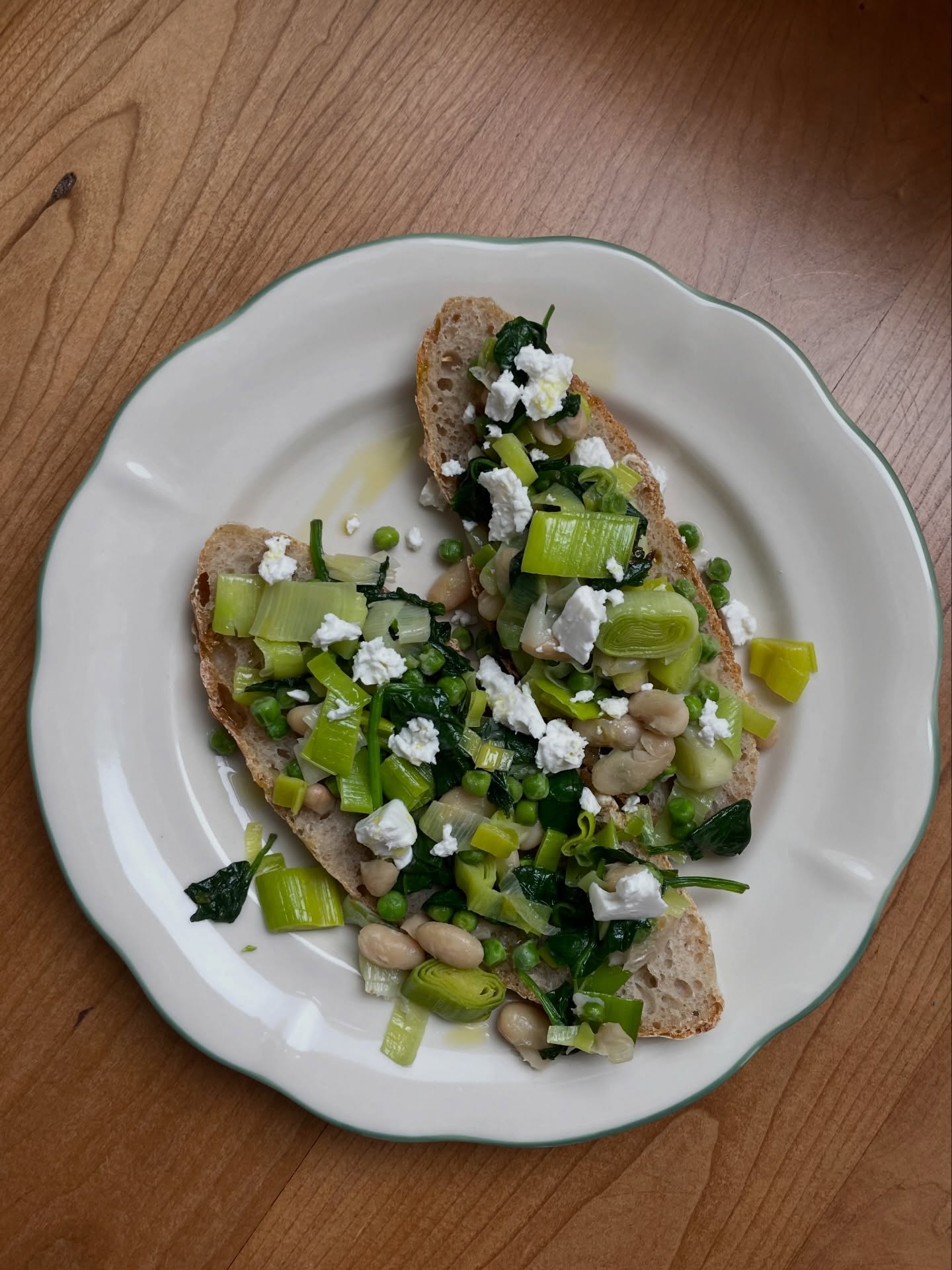 I love a hot meal and also love bread. This recipe combines the two, plus it has some great vegetable protein in it and is pretty much made out of things that happened to need using up in the fridge. It was delicious.
I made the sourdough myself, that is only down to the fact that I got given starter dough and now I feel the pressure to bake my own bread weekly. A great bakery slice will do absolutely brilliantly here. If you live in London try the little bread pedlar @lbpedlar .
Ingredients
For 2:
- 4 slices great sourdough
- Half a can of cannellini beans, drained
- One leek, cut into small pieces
- A handful of frozen peas 🫛
- A handful of spinach
- Small piece of feta cheese
- Olive oil
- Salt and pepper to taste
- Mayo
- Chilli 🌶️ oil optional
The greens in this can be substituted with all sorts of other greens e.g. green beans and broccoli are also perfect.
In a medium sized pan, start cooking the leeks in some oil on a medium heat and once the pieces start to be softer, add frozen peas and spinach. Add the beans at the end and cook for 3 more minutes, they should be hot but not disintegrating.
In the meantime, spread some mayo on the toast slices and then add the vegetable mix. Finish with some feta.
I usually finish this with some chilli oil that makes it even better. Enjoy!!
Sourdough, quick and easy lunch, vegetable protein ideas, cheap lunch