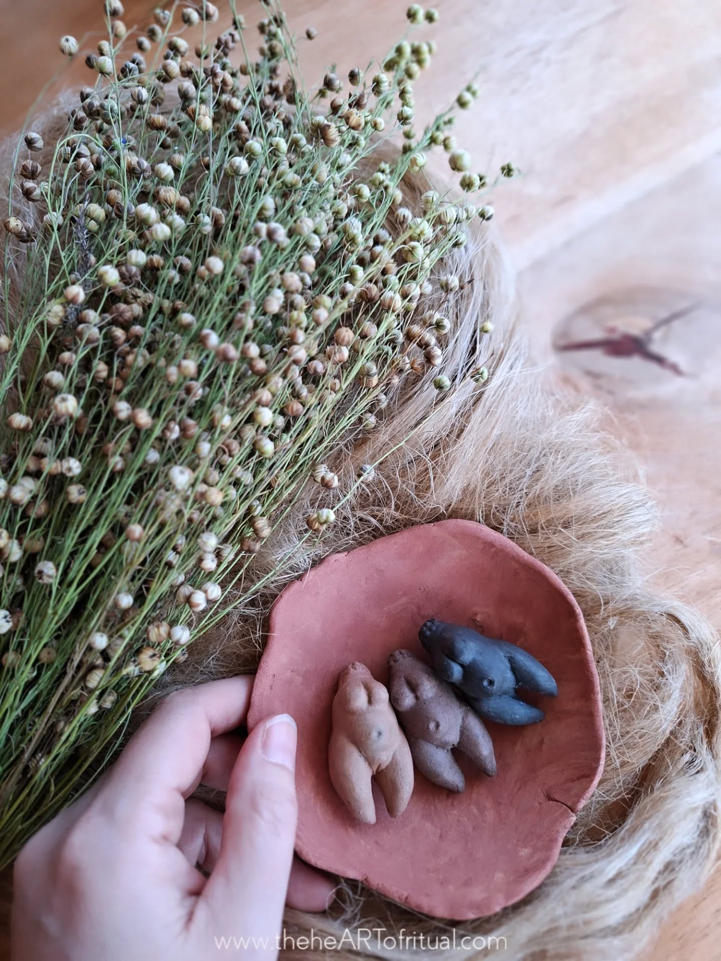 Within the vessel, newly fired clay rests beside flax still carrying its seed, materials gathered together before their work is complete. Earth and plant appear here at different stages of continuation: relics shaped by winter fire held alongside fibre drawn from stems that will return to soil as seed and continue forward as cloth.
The vessel does not contain but holds. The figurines remain in a state of arrival, carrying the quality of the newborn – forms emerging from earth and water, altered by flame, and resting in the brief interval between making and becoming part of daily life. Their surfaces bear the record of fire, where heat and ash moved according to their own logic rather than intention.
Beside them, flax shows both origin and outcome at once. Seed prepares for another growing season while fibre moves toward textile, toward cloth that will hold space and accompany acts of work and pause. The hands that shaped clay through winter now turn toward fibre as spring begins, carrying the same attention forward into another material.
Vessel, relic, seed, and fibre meet here at a threshold within the year. Each holds a different tempo of time, yet all belong to the same turning. Renewal does not begin anew; it emerges from what has already been prepared. Sacred space begins where continuity is observed and given form. Here, the journey into the growing year begins.
Seasonal writings continue through the newsletter, where the deeper threads of this work unfold alongside each collection as the year turns.
theheartofritual.com/seasonalnewsletter
_______________________________
The heART of Ritual
theheARTofritual.com
© 2026 The heART of Ritual™. All rights reserved.
#theheARTofritual