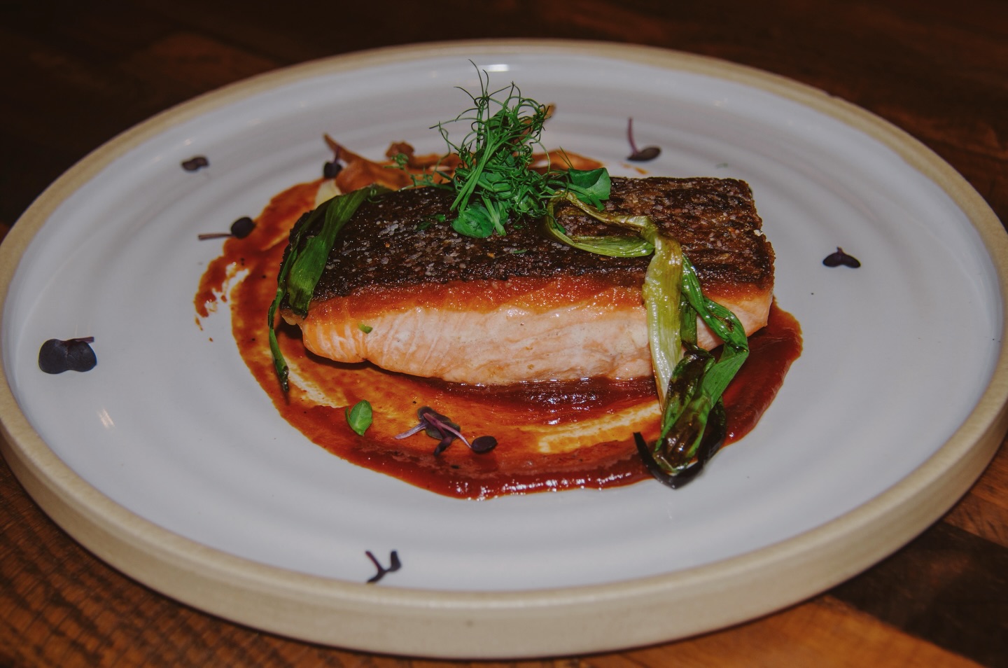 Treat your tastebuds to dinner with our Crispy Skin Salmon, perfectly seared to a golden finish and paired with crispy parsnip chips, roasted scallions, and a rich miso glaze.