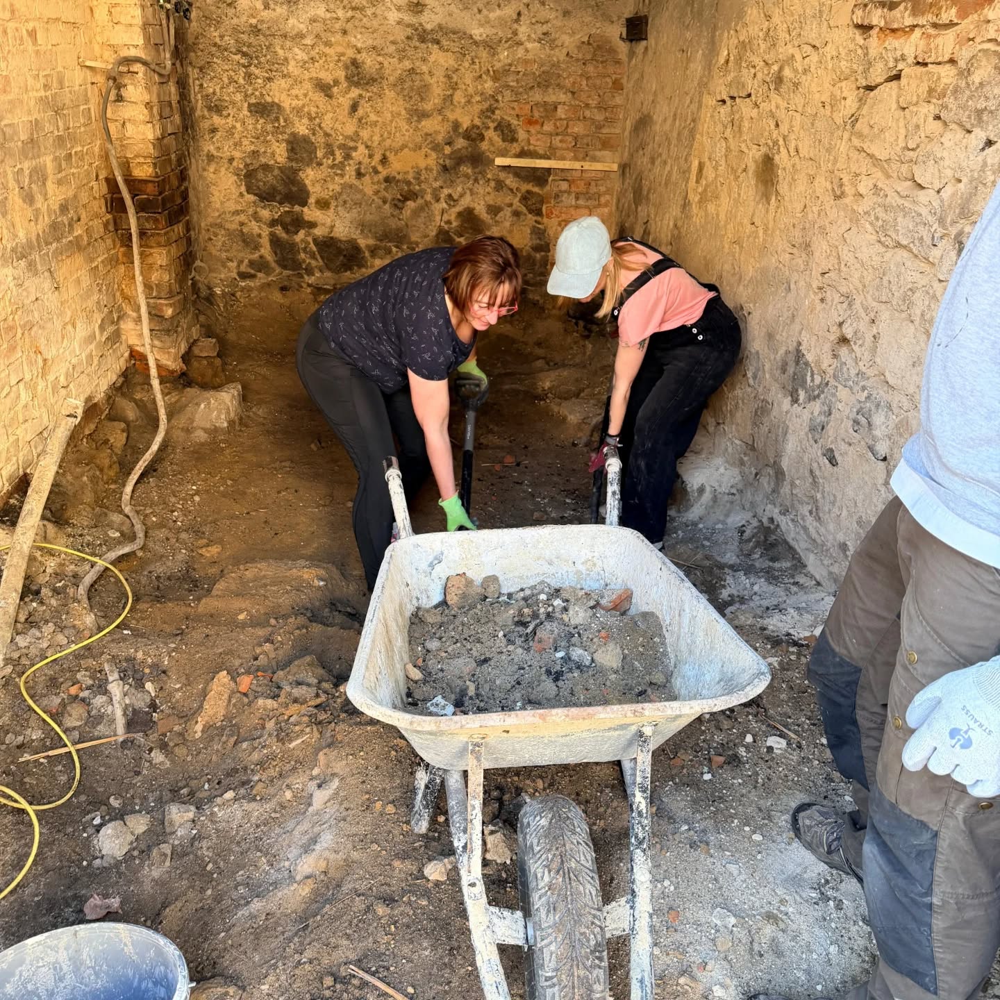 Liebes Tagebuch,
der Morgen begann heute wieder ganz romantisch. Also… unsere Version von Romantik: Steine klopfen statt Yoga. Während andere Menschen Vögel zwitschern hören, hörten wir das melodische klong, klong von Hammer auf Stein. Baustellenmusik eben.
Wie immer spielte sich das eigentliche Spektakel am Container ab. Dort wurde geklopft, philosophiert und der letzte Mädelsabend in Löbau durchgenommen. Wer kam dem heißen Männerkörper bei Striptease am nächsten, welche Dame hat sich dem erotischen Lap Dance im Männenschoss hingegeben? Spätestens da wusste jeder: Das Gesprächsniveau hat wieder seinen ganz eigenen Baustellenstandard erreicht.
Währenddessen haben Steffi und Alina den Boden in der Werkstatt weiterbearbeitet. Schippe für Schippe, Schicht für Schicht. Und was kam zum Vorschein? Steine, die vermutlich schon dort lagen, als die Dinosaurier hier ihre Mittagspause gemacht haben. Das Ergebnis? Ein Loch. Nicht irgendeins. Nein, wahrscheinlich das Wichtigste im ganzen Haus, um neben den Ideen aus den Köpfen, auch den Mist aus den Körpern heraus zu befördern. Ein Schacht für glühende Lampen und für das berühmte Scheißerohr.
Im Fließbandakkord wurden die brauchbaren Steinchen zum Rest der Container-Crew gebracht, um sie ganz nach Vorgabe aufzupolieren. Manchmal sauberer als mancher Badspiegel daheim.
Für Unterhaltung sorgte René, der hingebungsvoll mit seinem Lieblingswerkzeug spielte. Welches genau das ist, bleibt ein kleines Baustellengeheimnis… aber er war sichtlich zufrieden damit.
Dann kam das Highlight des Tages: die erste Einrichtung!
Mit einem breiten Lächeln und leuchtenden Augen, nahm Enno ,René und Matthias die großartige Markisenspende von Jirtka & Andrea entgegen. Keine Zeit zum Nachdenken. Abbauen, transportieren und gleich wieder an die richtige Wand im Hof dübeln Perfekt für zukünftige legendäre Sommerpartys im Hof – mit Schatten, Musik und Leuten, die sagen: „Ich geh gleich… nur noch ein Lied!“
Natürlich durfte auch der Kaffeeklatsch in der Sonne, ganz standesgemäß auf unserer historischen Schlittensammlung nicht fehlen. Mit dabei: Alina, Steffi, Doreen Maria und wie sie alle heißen… Schlitten? Warum? Gute Frage. Vielleicht, damit