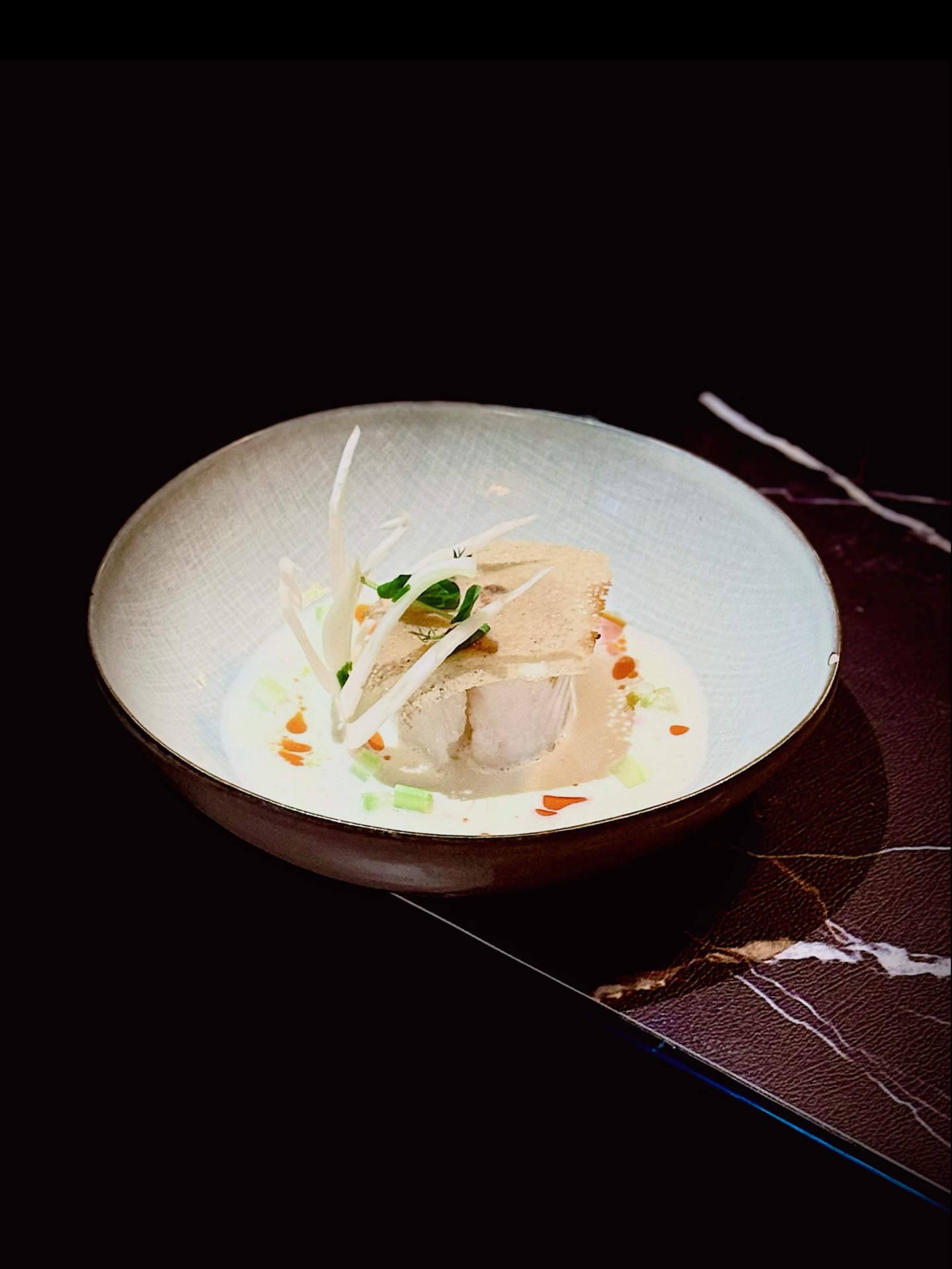 La carte du Soir - La saison de Jīngzhé, Chūnfēn et Qīngmíng
【Harmonie Claire, Tonnerre Voilé | 清和•雷隐】
De Jingzhe 🐞🌱 à l’Équinoxe de printemps ⚖️🌸, puis jusqu’à Qingming 🌿🌧️, la saison s’éveille, s’équilibre et se clarifie. Ce cabillaud poêlé 🐟 en est l’écho — une composition douce, lumineuse et vivante.
Le cabillaud est saisi délicatement 🔥, doré en surface, nacré et tendre à cœur. Le bulbe de fenouil 🌿, croquant et légèrement anisé, apporte une fraîcheur végétale, comme une herbe neuve après la pluie 🌧️.
Le Jiangshui 🥬 est une préparation traditionnelle du Henan, issue de la fermentation naturelle de légumes verts comme la moutarde ou le chou chinois. Son bouillon légèrement trouble développe une acidité fraîche et vivifiante.
Dans les campagnes du Henan, on l’utilise pour préparer les fameuses nouilles au Jiangshui 🍜, ou simplement comme boisson rafraîchissante en été ☀️. C’est un goût humble, mais profondément enraciné 🌾.
Son acidité douce soutient l’appétit et éveille le palais sans l’alourdir.
Dans cette version émulsionnée ✨, le Jiangshui est lié à un filet d’huile ou de fond, créant une texture soyeuse, presque veloutée. L’acidité devient caresse, soutenue par la rondeur de l’émulsion.
Elle souligne la douceur du poisson et dialogue avec l’anis délicat du fenouil, dans une harmonie claire et mesurée. Une assiette limpide comme l’eau de printemps 🌊 — où la tradition rencontre la mer. 🌸
从惊蛰 🐞🌱 的初雷,到春分 ⚖️🌸 的均衡,再到清明 🌿🌧️ 的清朗,春意在天地之间缓缓铺陈。这道 煎鳕鱼 🐟,正是在这一段时序里诞生的味觉诗篇。
鳕鱼表面轻煎至微金 🔥,内里仍如晨雾般柔润细腻。茴香球 🌿 清脆甘甜,带着淡淡草本与微微茴香气息,仿佛雨后新芽在空气中舒展 🌧️。
浆水 🥬 是河南流传已久的民间滋味。它以芥菜、白菜等绿叶蔬菜自然发酵而成,汤色微浊,味道清酸爽口。
在河南乡间,人们常用它煮成 浆水面 🍜,或在夏日清饮解暑 ☀️。这是一种朴素却深深扎根于土地的味道 🌾。
它的酸味温和而清醒,既开胃,又不会给味觉带来负担。
在这道菜中,浆水被轻轻 乳化 ✨,与油脂或高汤融合,使质地变得柔滑细腻。酸味被包裹、被抚平,如春水绕石,圆润而有光泽 🌊。
它托起鳕鱼的鲜甜,也与茴香的清香相互呼应,让整道菜在轻盈与深度之间取得平衡,如春分昼夜的均衡。
这一口,是春雷后的第一缕清风,是春水初融的温度,也是清明时分的明净与从容 🌸✨。
📝 Reservation (预订) : www.bistrowu.com
#aixenprovenceweed🔥🍁❄️☘️ #printemps #aixmaville #aixenprovence #cuisinechinoise