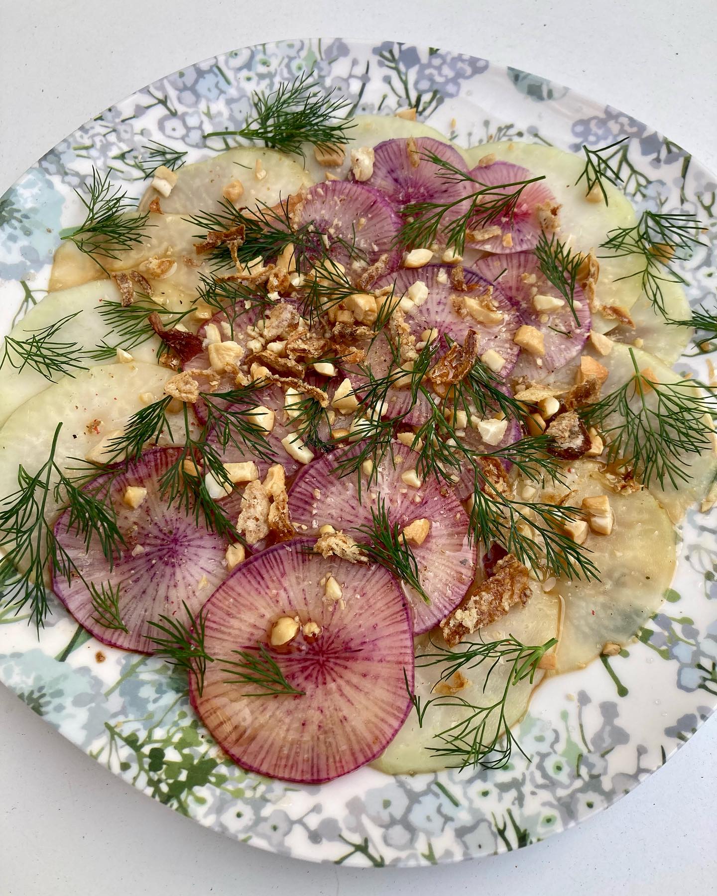 Carpaccio de chou rave et radis violet!
Le chou rave est plus savoureux cru que cuit, il a ce délicieux petit goût de noisette, très subtil. Il pourrait juste être servi cru, en croque au sel, pour l’apéro. Je le trouve parfait coupé très finement, si possible à la mandoline (si vous ne craignez pas pour vos doigts), mariné pendant quelques heures, histoire de le cuire un peu et de le rendre plus digeste. Pour que ce soit encore plus beau, je l’ai associé à un radis violet coupé finement, et lui ai ajouté au dernier moment un peu d’aneth et de noix de cajou écrasée!
Pour 4 personnes: 1 chou rave, 1 radis violet, 2 c.à soupe de sauce de soja et de vinaigre de riz, 2 c.à soupe d’huile de sésame grillé, 2 c.à soupe d’huile neutre, quelques feuilles d’aneth, 1 poignée de noix de cajou grillées, 1 c.à soupe d’oignons frits (facultatif), sel, poivre.
Éplucher le radis et le chou rave, les couper en tranches très fines. Mélanger dans un bol le vinaigre, la sauce de soja et l’huile.
Dans des assiettes individuelles, repartir les tranches, les couvrir de sauce. Couvrir d’un film et laisser mariner quelques heures, voir une nuit.
Écraser légèrement au pilon les noix de cajou.
Les ajouter au dernier moment, avec l’aneth et les oignons frits. Saler légèrement, poivrer.
Servir frais!
Bonne dégustation!
NB: Pour les bienfaits du chou rave, selon la Diététique Chinoise, je vous conseille mon article précédent.
#chourave #radis #radish #radicchio #carpaccio #carpacciolovers #cru #cuisinemaison #joli #dietetique #dietetiquechinoise #madreperlamtc