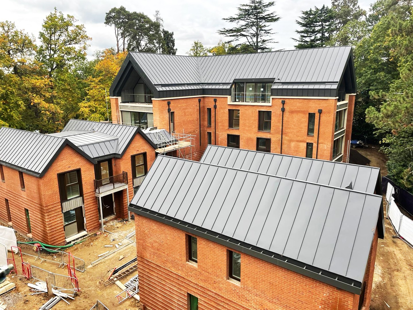 Sunningdale, Ascot. An ongoing, residential development for Henry Construction Projects Limited (Architects: Gaunt Francis architects).
AMR have full design including associated substrates on this project.
This project consists of Bauder Thermafol U15 anthracite grey PVC single ply warm roof construction, Falzonal 0.8 matte dark grey standing seam roofing on a warm roof construction and pre-formed aluminium gutters. All spanning over 5000sqm.’