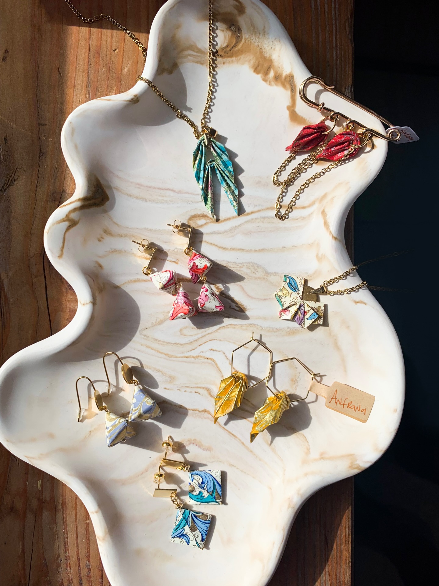Une feuille de papier, quelques plis, une bonne dose de technique et de talent… et un bijou apparaît ✨
Depuis le 1er mars, c’est avec plaisir que nous proposons les créations de @anfrana_bijoux. Sa spécialité? Transformer le papier en bijoux délicats grâce à l’art de l’origami. Chaque pièce est pliée à la main, puis protégée pour devenir un bijou élégant, graphique et léger, tout en étant résistant.
Un vrai travail de précision, une sélection pointue de papiers venus d’Italie, d’Inde, du Japon ou du Népal… et ce petit côté « comment c’est possible avec du papier? » qu’on adore.
Les bijoux @anfrana_bijoux sont ici présentés sur un plateau @julieresin.co, créatrice d’objets déco tendance en Jesmonite, également arrivée à la boutique début mars!