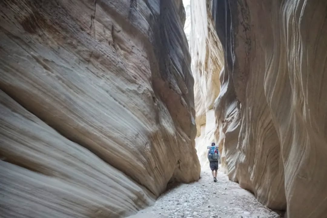 Hayduke Day 22 || Paradise Canyon to Hackberry Creek
Another night of rain, but at least without the wind. I can sleep through that. And anyway, if there's going to be rain today, better through the night and early morning than at the end of the day when it could be fatal…
Most of the day was fast travel along jeep roads which eventually brought me to the day's first highlight - Grosvenor Arch. Actually a double arch, very high and narrow. Very cool.
After an afternoon break at the arch where I helped some German tourists try to find the landmarks they were looking for, I eventually hiked out the next five-ish miles to where I'd drop into the Round Draw Narrows (slot canyon!!). Just getting down into them was tricky enough, and the first time along the trail where I had to lower my pack on a rope ahead of me and then climb down after it. The body positions needed to down climb just wouldn't have been possible with it on. Later I had to lower my pack again, past a large chock stone requiring another narrow down climb through a gap. Despite the obstacles, or possibly because of them, these narrows were one of the highlights of the whole trail so far. So wild to reach out and touch both walls but also look up and not even see the sky. Thankfully I had good weather going in, but these are the spots you definitely don't want to be if it's raining - nowhere to run if the wall of water catches you down there. All I had was some mud.
After exiting the narrows section, the canyon joined the larger Hackberry Creek where I hiked a few more miles and made camp. Didn't find water but I've got plenty left from today's carry due to the cool temps. Supposed to drop to freezing tonight.
#thruhike