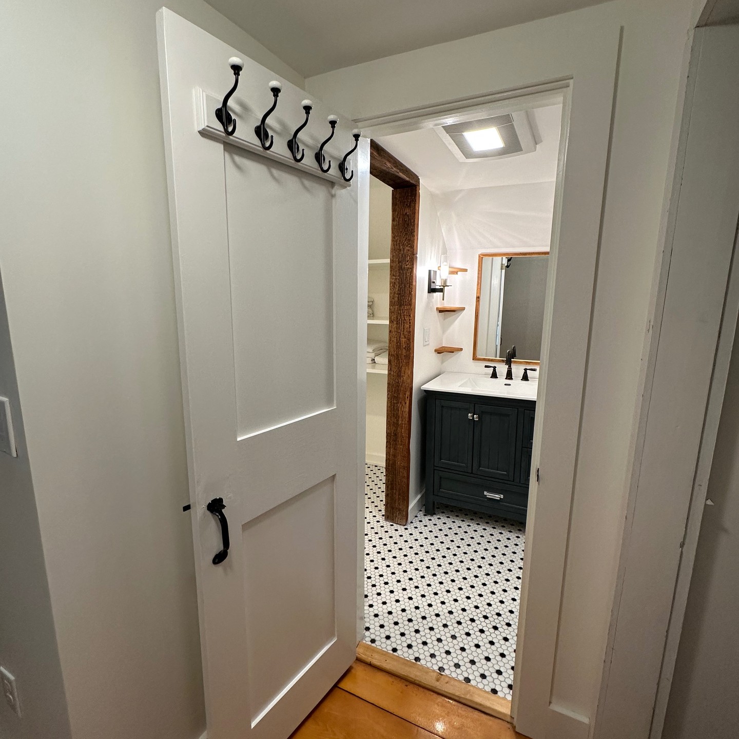 Adding a bathroom to the second floor landing of a 1800 farmhouse was a bit like building inside a crushed beer can. Luckily, we had a great client that was ok with flat, not level. Custom shower and shelving, corner shelves/mirror frame made from their old floorboards, and adding an interior window made this project feel as unique as this old house. #Vermont #carpentry