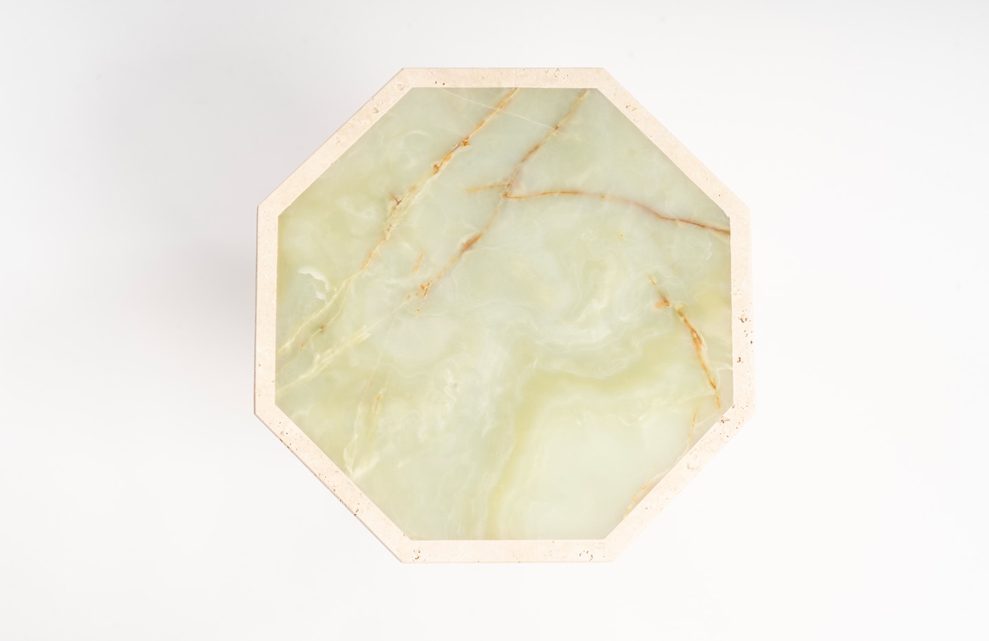 La pierre comme architecture.
Chaque pièce est composée de strates de travertin sculptées une à une, formant une silhouette octogonale presque monolithique.
Au sommet, un plateau en onyx vert capte la lumière et révèle ses veines naturelles, comme un paysage minéral.
Une présence discrète mais sculpturale, pensée comme une pièce de collection qui dialogue avec l’espace.
Fabrication artisanale - chaque pièce est unique.