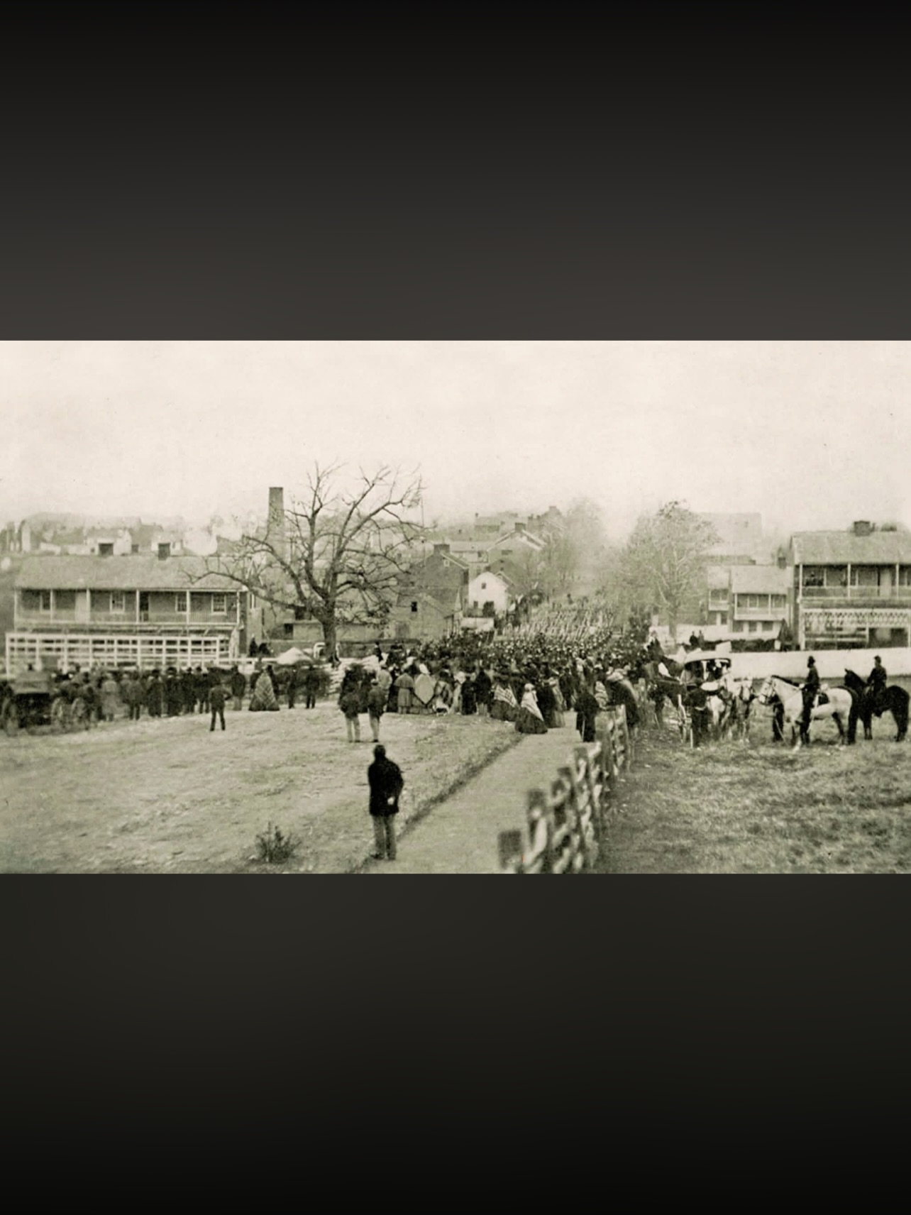 LINCOLN COMES TO GETTYSBURG
The Northern Central Railway Station at Hanover Junction, PA, taken in November. Lincoln made the train connection here on his way to Gettysburg to consecrate the National Cemetery. Historians differ on whether the man on the platform is the president, along with his Secret Service people. The man in question is obviously much taller than everyone else. Lincoln was 6’4 while the average height for men was 5’10. That, the timing of the photo, and his trademark stovepipe hat definitely suggest that it is the president.
Back in Gettysburg, Union troops march down Baltimore Street as locals pour out to welcome them. The unit was part of the National Cemetery dedication. Note the Shriver House, the large white house right at the center of the image. The window on the upper floor was the location of Confederate sharpshooters during the street fighting on day one.