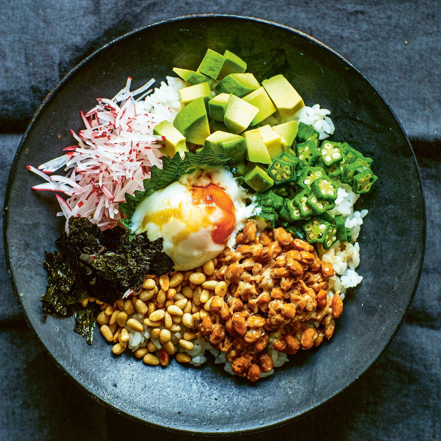 Never Never Don
Fancy a challenge?
With this dish, you will see whether you have true Japanese taste! The rice is topped with sticky natto (fermented soy beans), which is known to be a super nutritious food and contains a high volume of probiotics which help your gut’s health and build stronger immunity. There is no doubt it is good for you!
In Japan we overwhelmingly enjoy this sticky, slimy, texture called a ‘neba neba’. A European friend of mine wasn’t keen on natto and said he would ‘never never’ eat it. I renamed this dish ‘Never Never Don’ after him. Let’s see what you make of it! To ease you in gently, I have added other toppings to give a pleasing variety of textures. The onsen tamago or ‘hot springs egg’ is an egg that is slowly poached in warm water, which gives a soft silky white and custard-like yolk. You will enjoy the harmony of textures!
Why not take a video selfie when you try natto, tag us to share your reaction!
Here is my son’s😆
#nattochallenge #recipeoftheday #recipeshare #healthyrecipes #healthyrecipeshare #vegetarianmeals #homemadefood #homecook #homecookedfood #eatyourveggies #foodie #natto #onsentamago
This recipe is from my cookbook and shared it on my bio! #atsukosjapanesekitchen
@rylandpetersandsmall
The first picture of never never donburi by @yukisugiura.photo